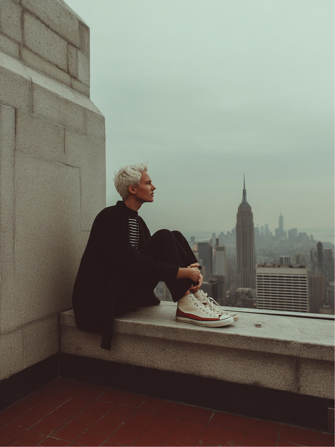 Person sitting on a ledge overlooking New York City skyline