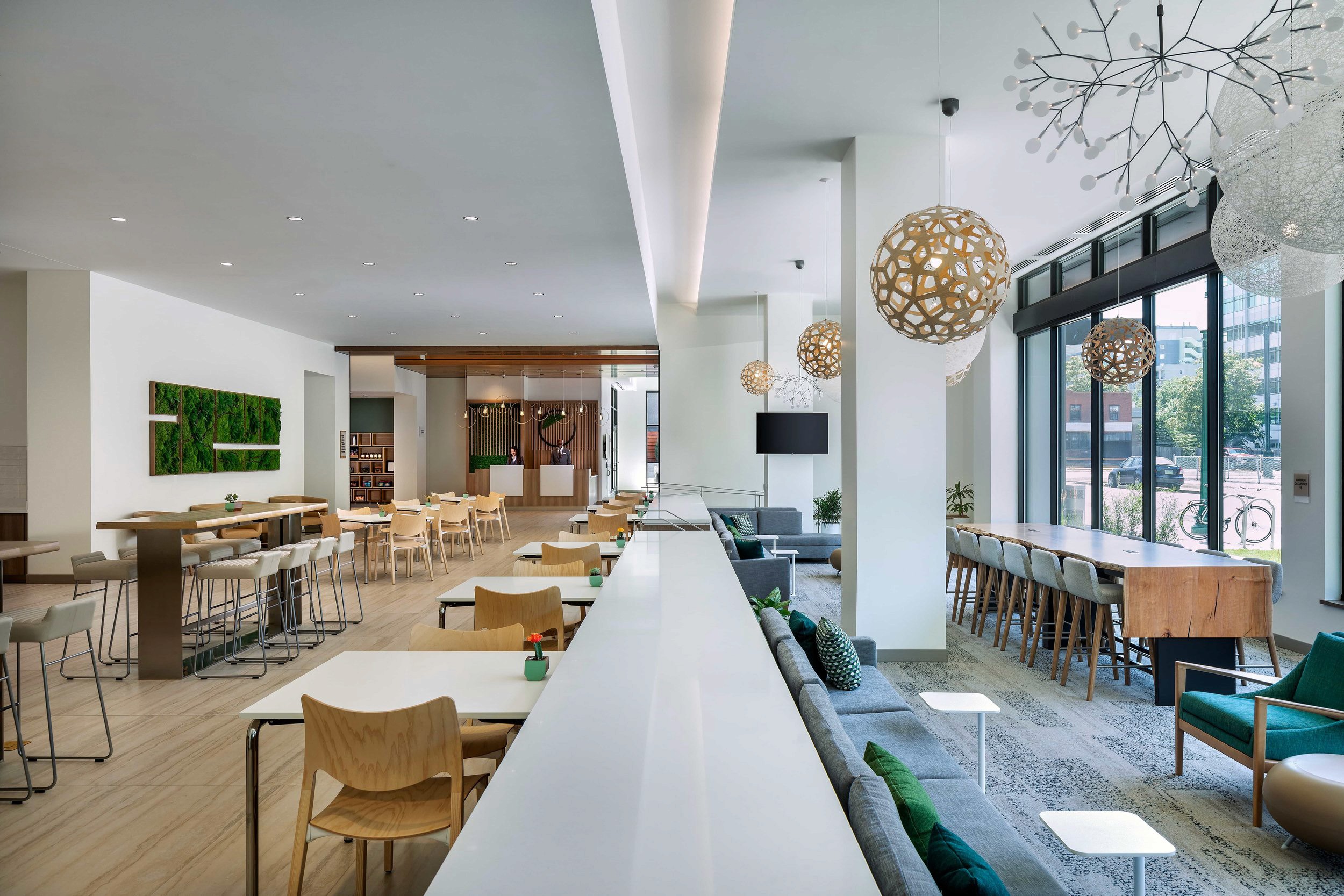 Modern hotel lobby with seating, tables and large windows.