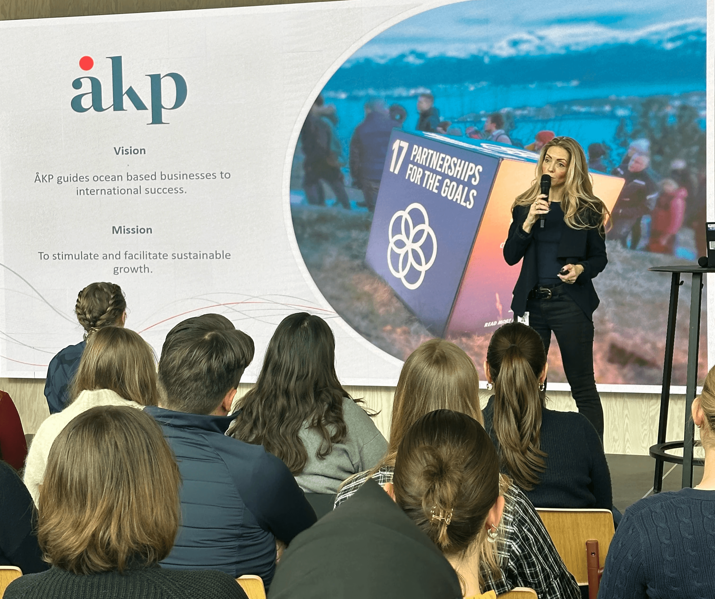 A person wearing a virtual reality headset stands in front of multiple screens, engaged in a digital experience.