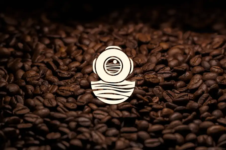 Copper Coffee Co. diving helmet symbol on a bed of coffee beans