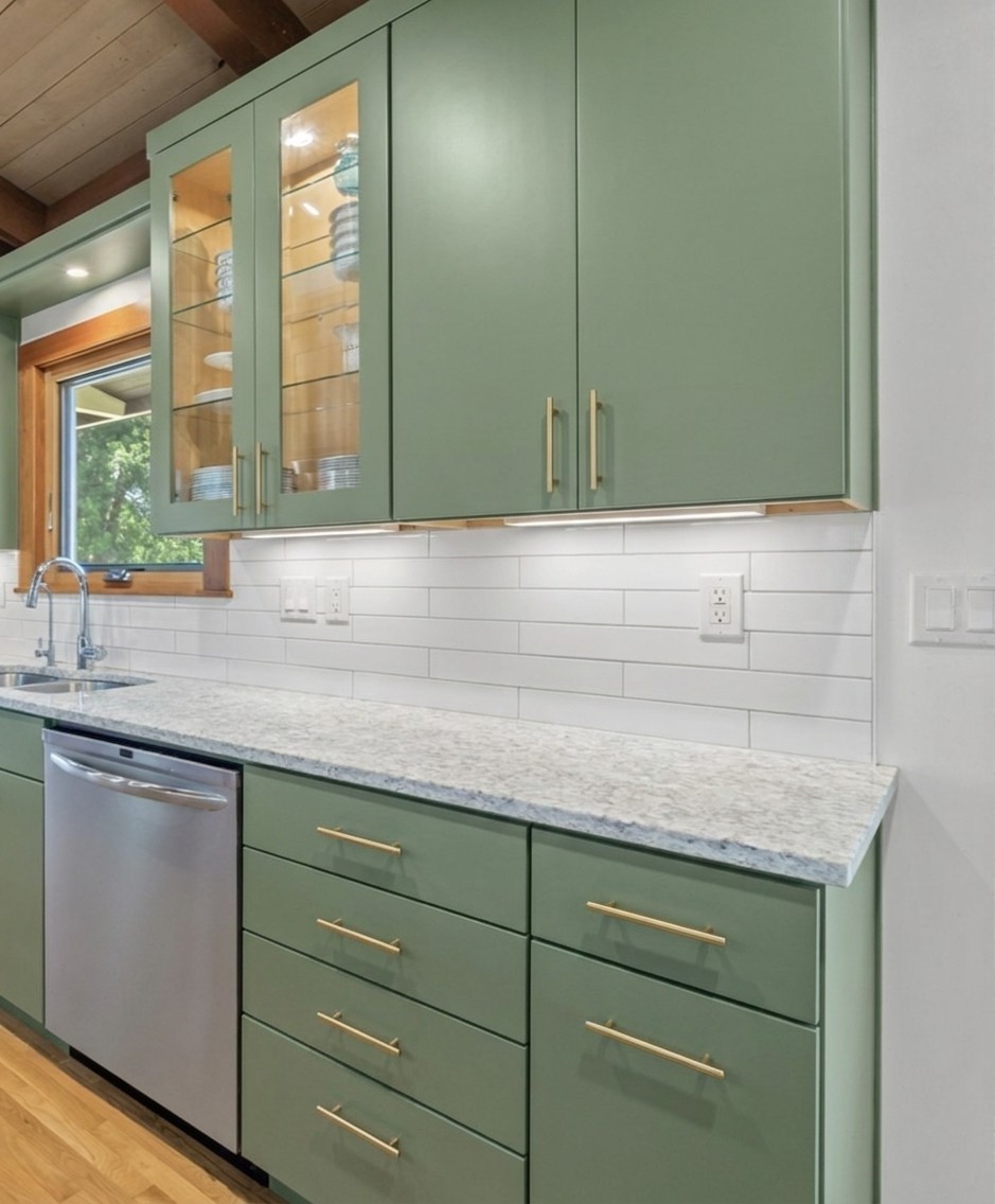 Sage green slab MCM — flat doors painted muted sage, white backsplash, MCM hardware