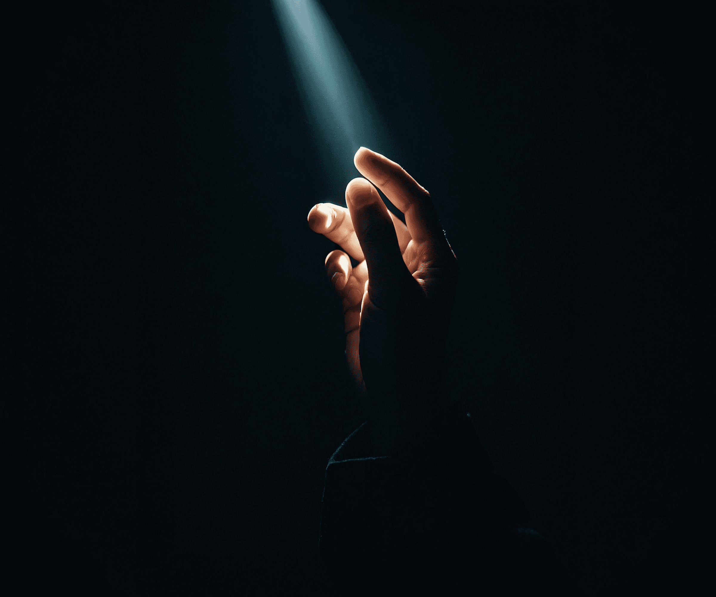 Hand reaching toward beam of light in darkness — representing the moment of finding the real problem behind product failure and user experience breakdown