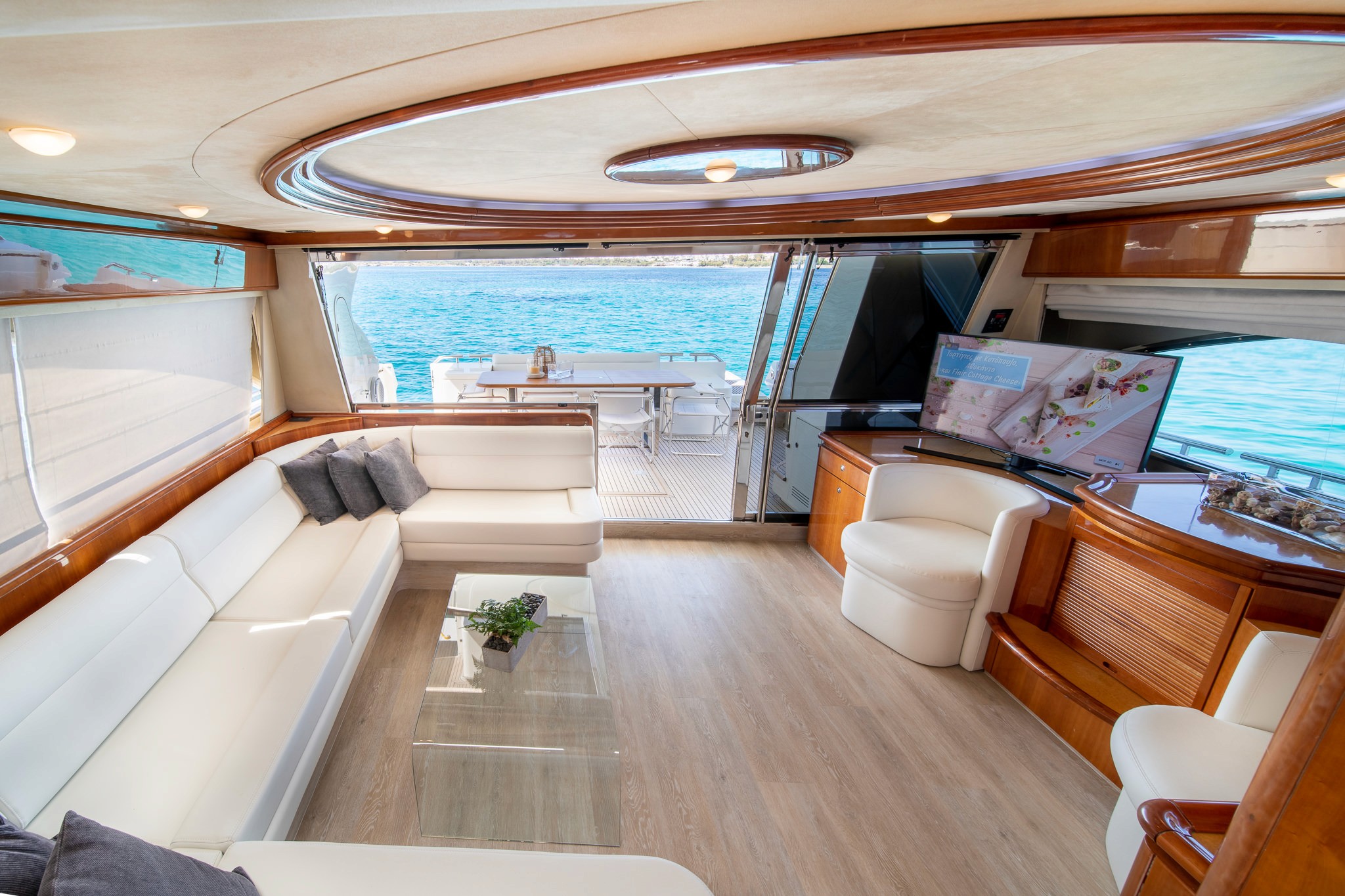 Luxurious yacht master cabin featuring polished wood finishes, white bedding, built-in storage, and flat-screen TV with steps leading to upper deck.