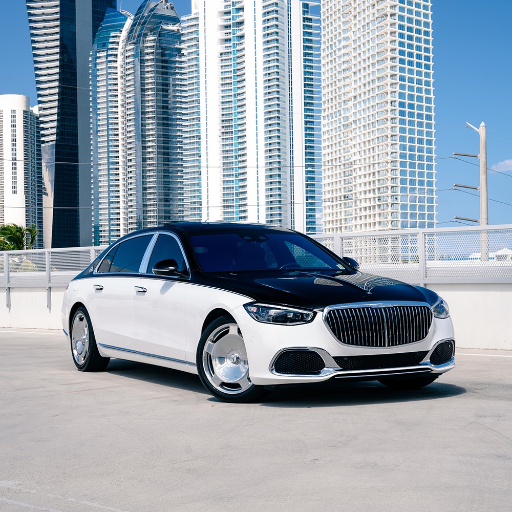 Front 3/4 view of a two-tone (white over black) Mercedes-Maybach S580 rental in Miami, showcasing its majestic presence and elegant design.