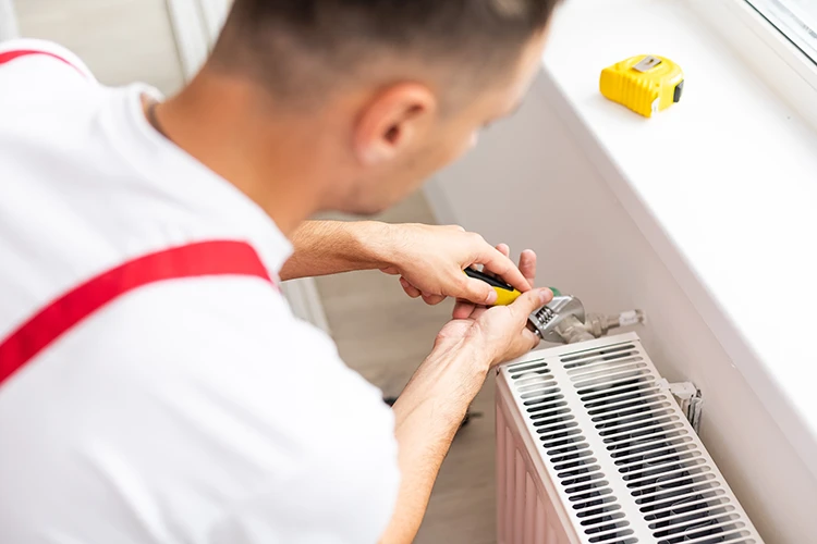 Blurred background image of an HVAC technician's hands carefully repairing the internal components of a heating unit.