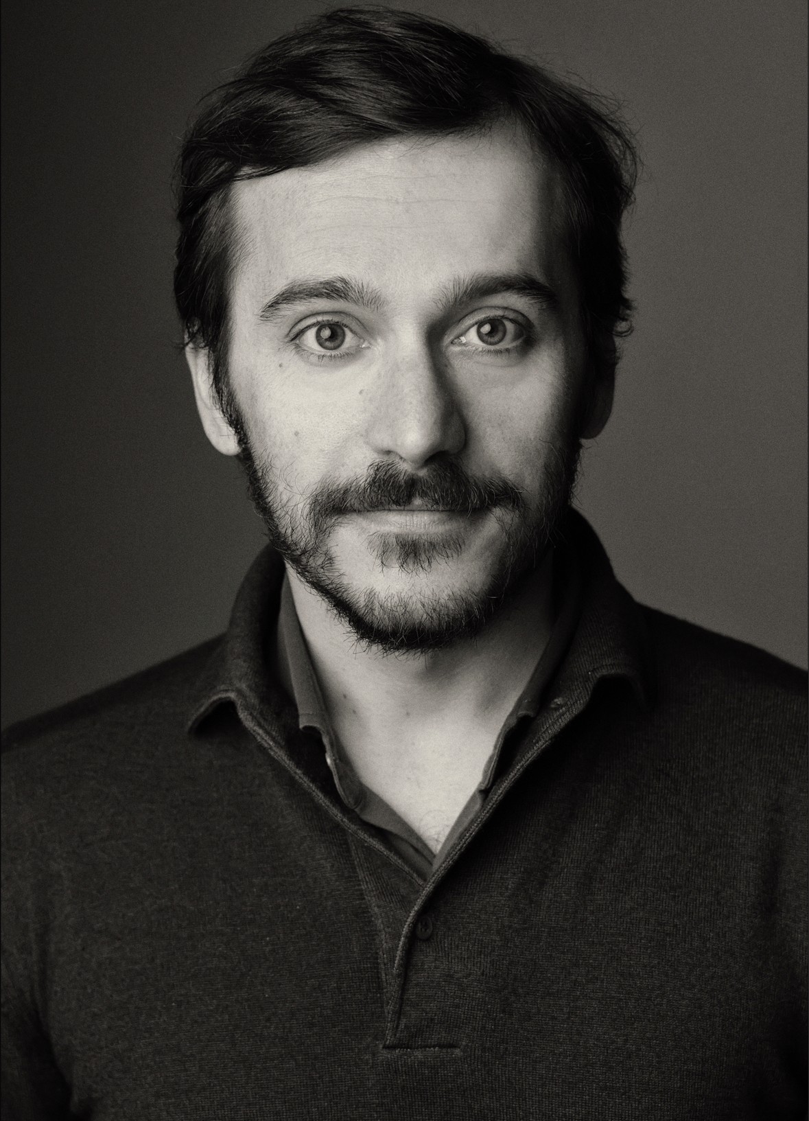 Young woman in a white shirt with a colorful gradient print, against a plain background.