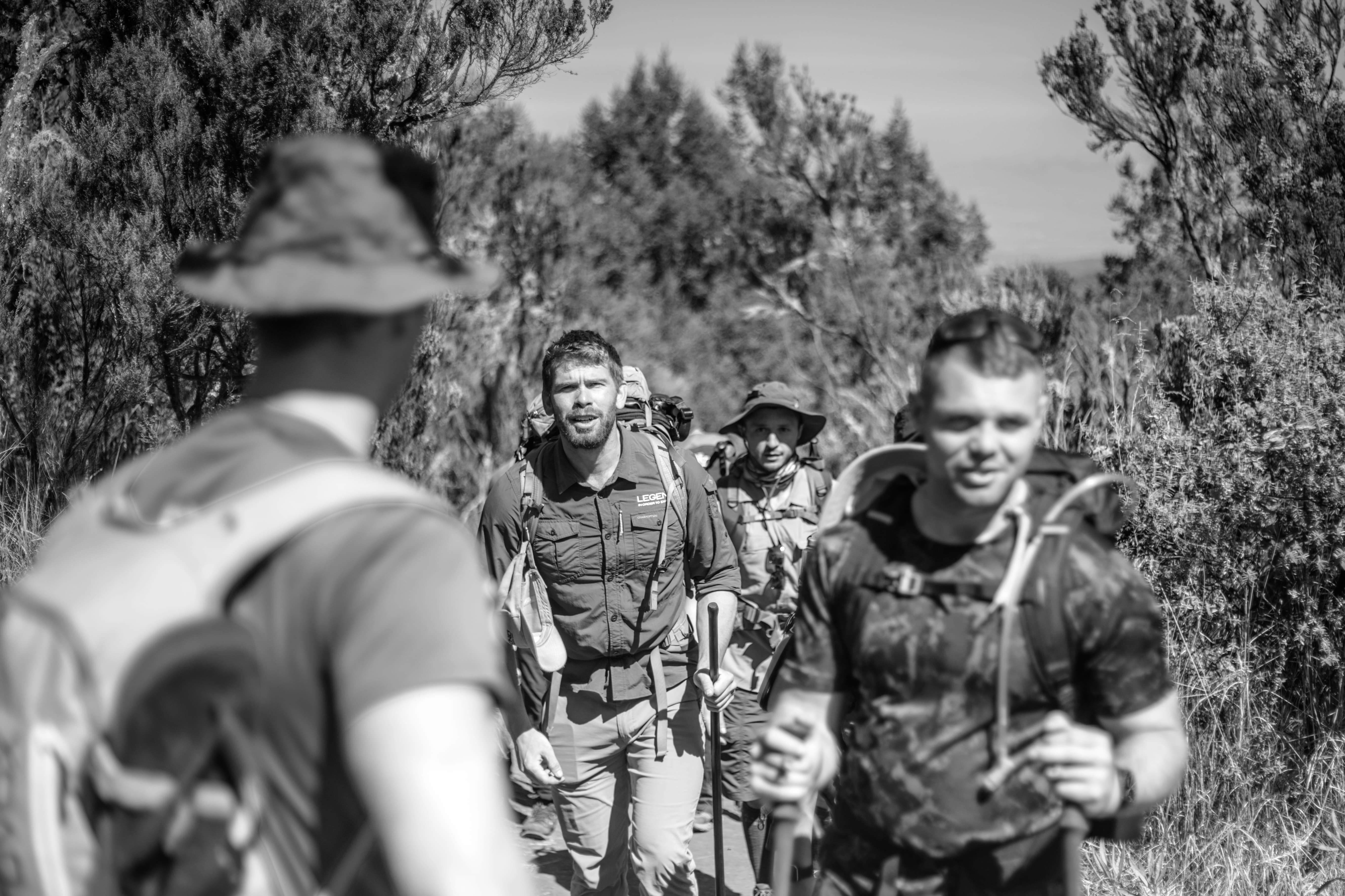 Climber and Legend guide hiking through Lemosho rainforest on day one of an 8-day Kilimanjaro expedition.