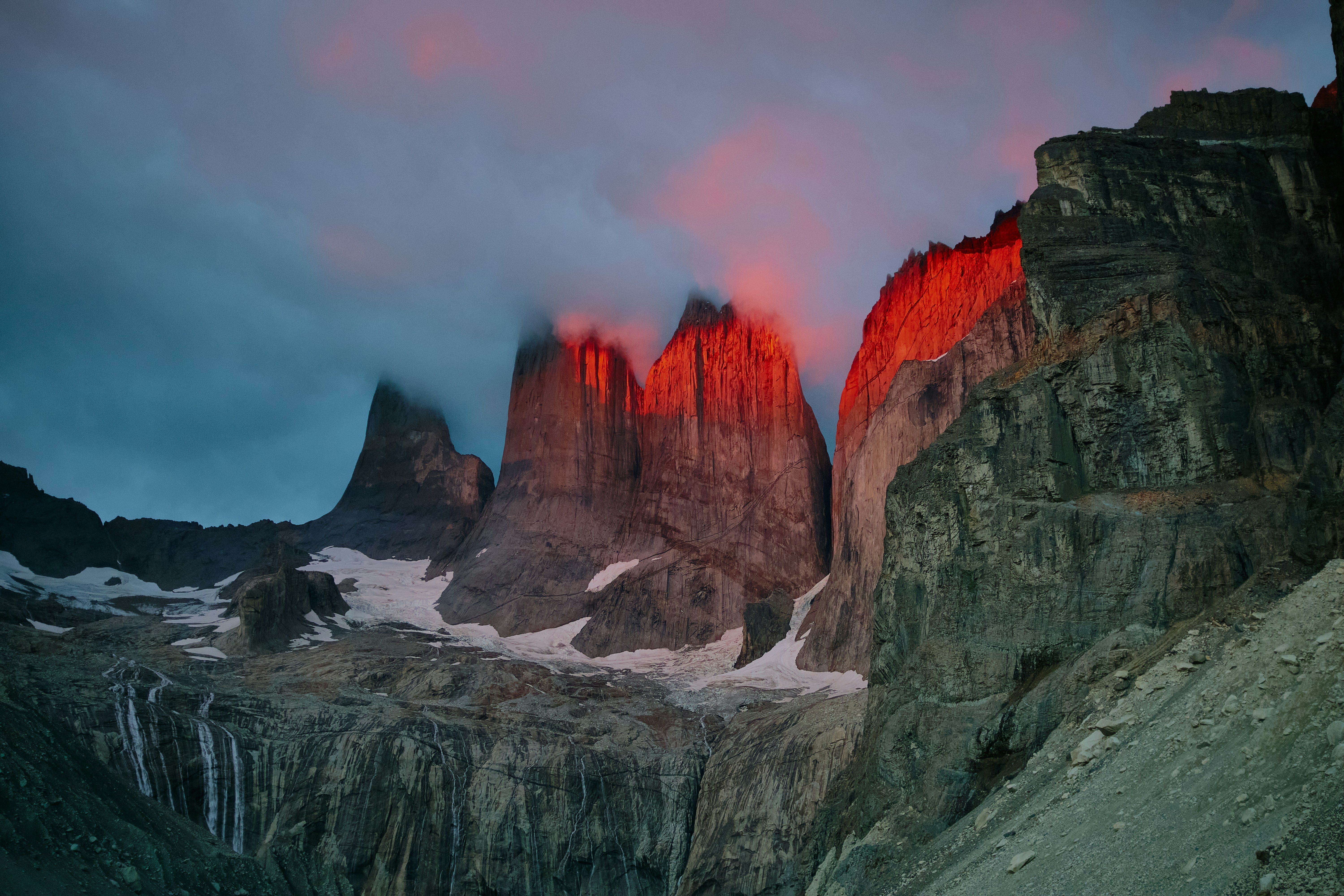 Mountain peaks glowing red at sunrise with snow.