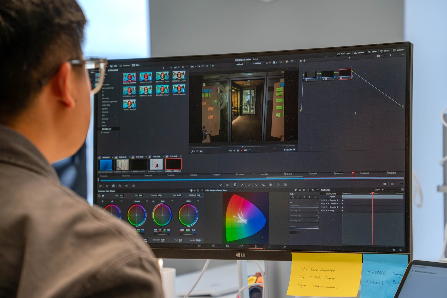 Person mit Brille vor einem Monitor, auf dem eine Farbkorrektursoftware mit Farbrad und Videovorschau geöffnet ist