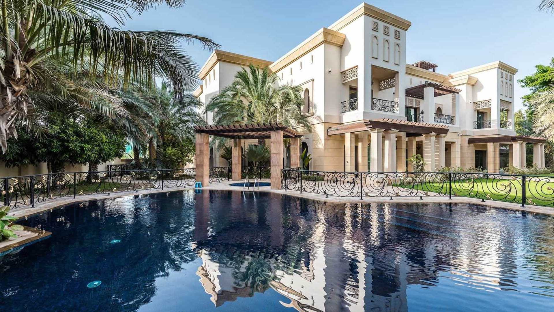 Building entrance in Emirates Hills, surrounded by palm trees and several cars.