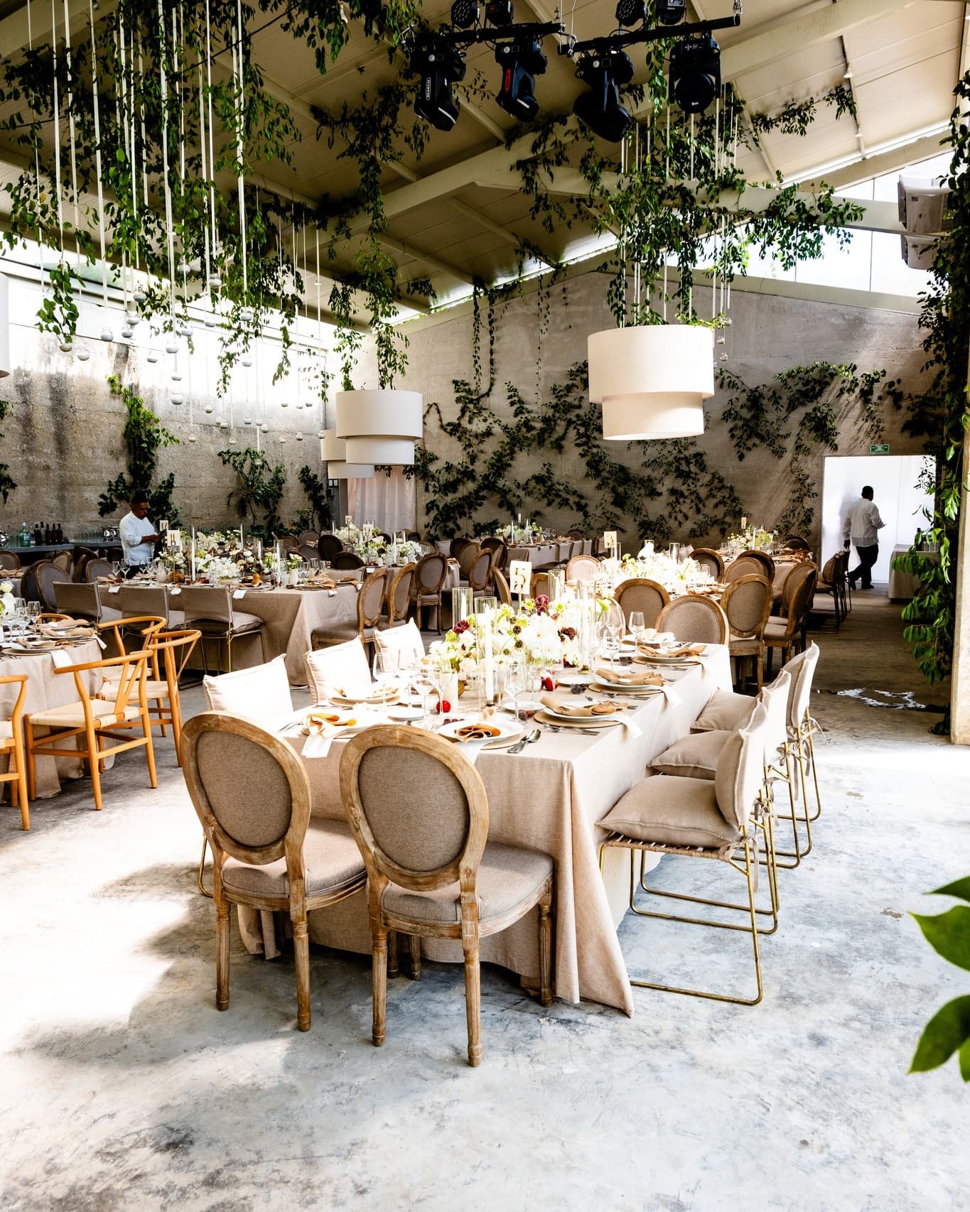 A beautifully set dining table with white tablecloth, cutlery, and fresh greenery in a cozy, well-lit space.