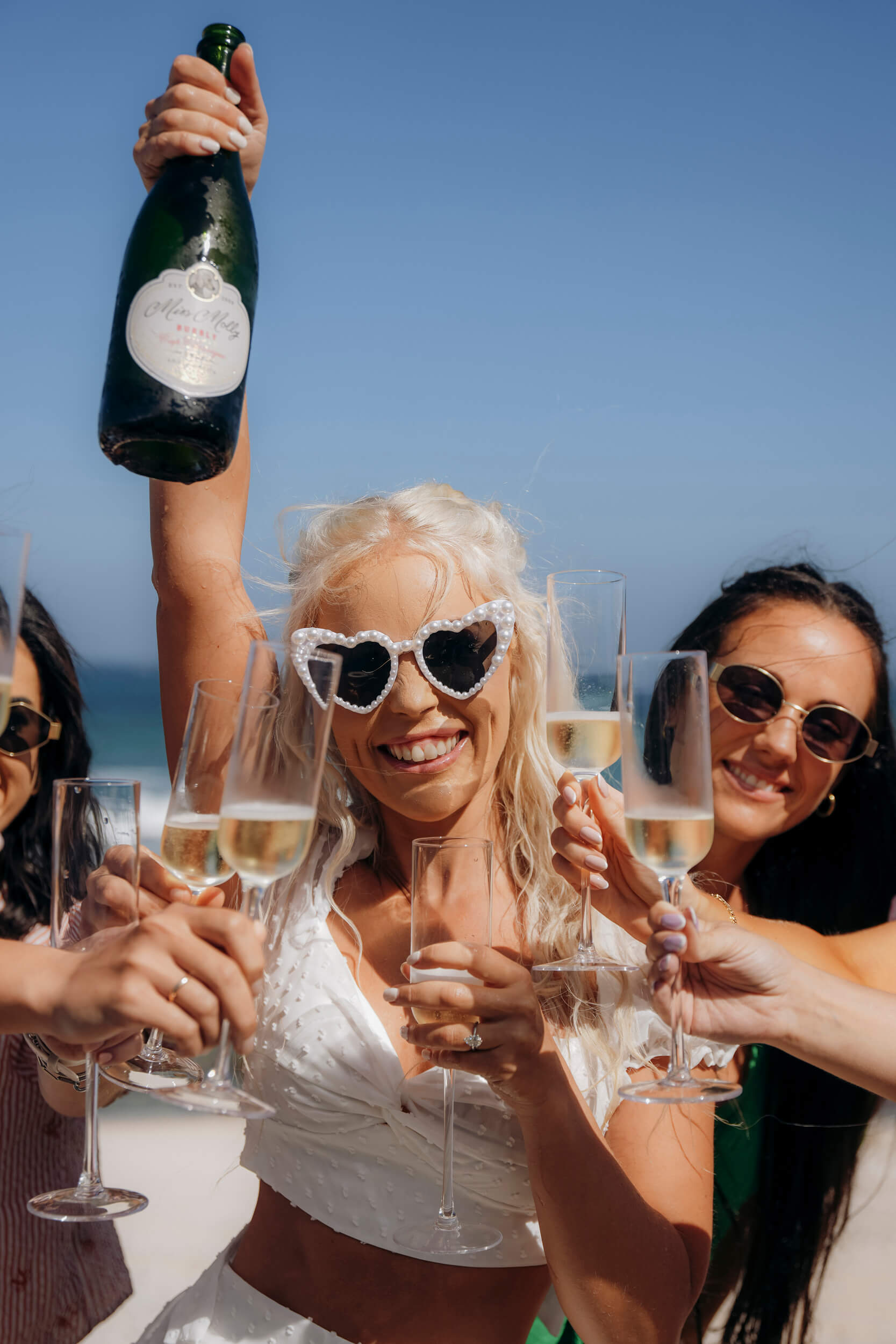 Bride celebrating with bridesmaids pouring champagne during wedding morning