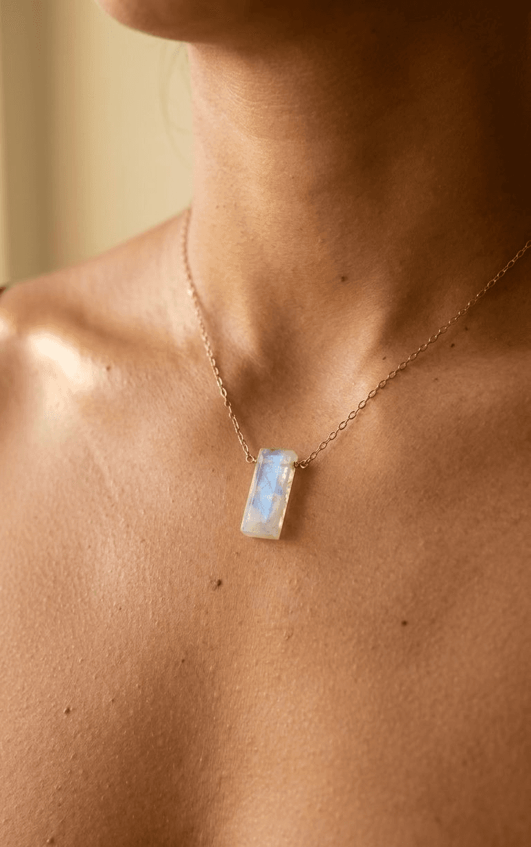 Rectangular iridescent stone pendant on a delicate gold-toned chain worn around the neck.