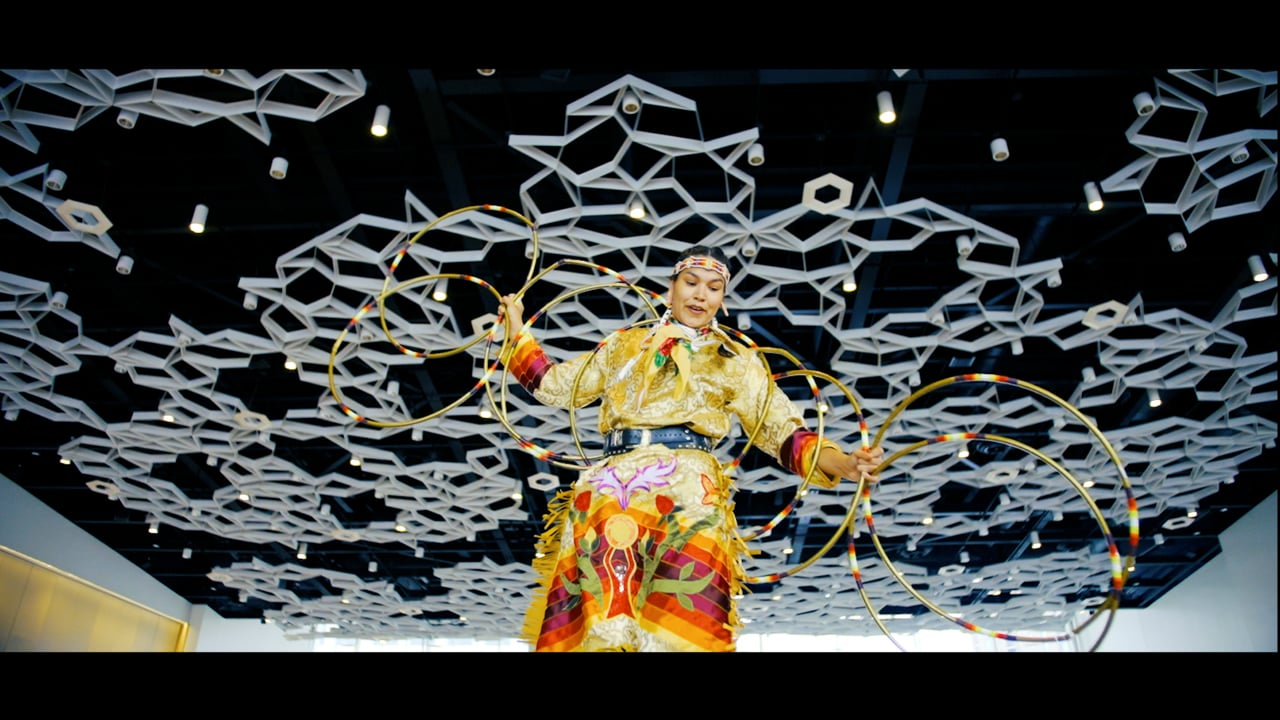 Person in indigenous clothing performing with hoops.