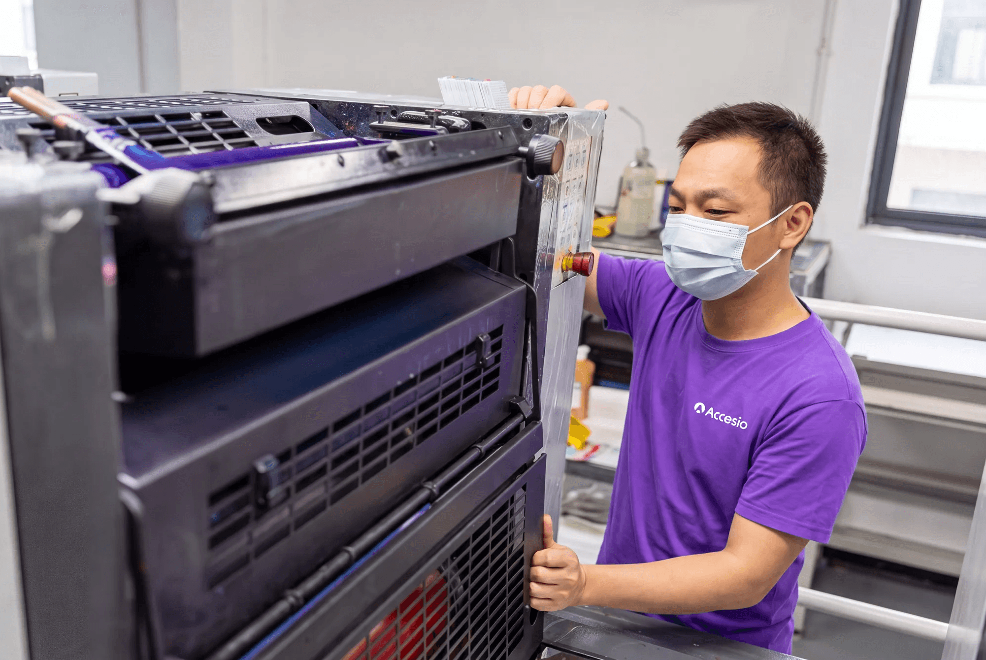 Accesio operator checking printed sheets on the press during a production run
