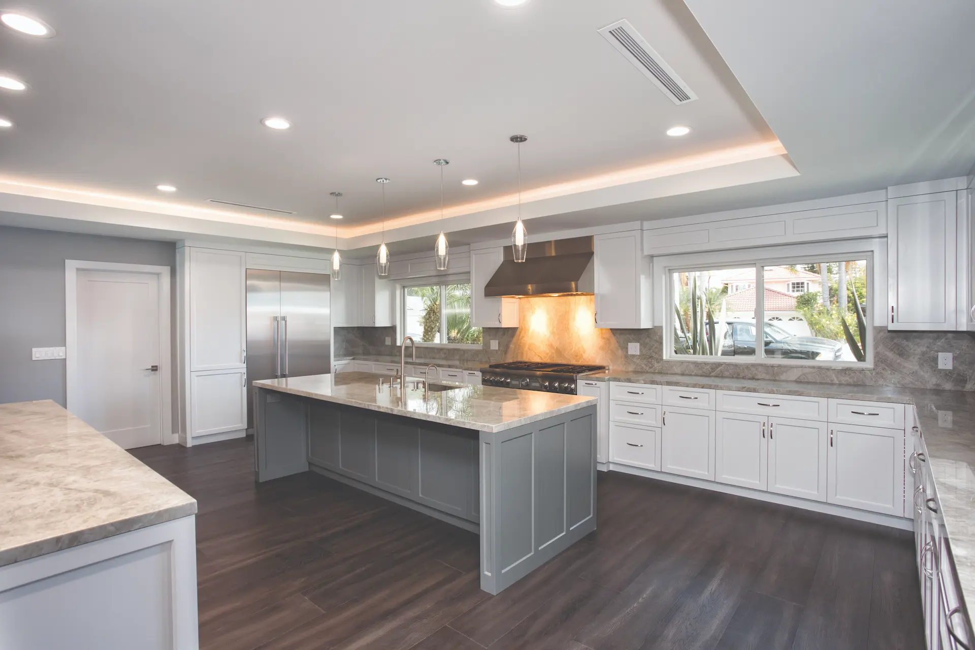 Modern kitchen angle showing contrasting island, granite countertops, and stainless steel appliances in Costa Mesa Remodel. Photo by Chris Darnall.