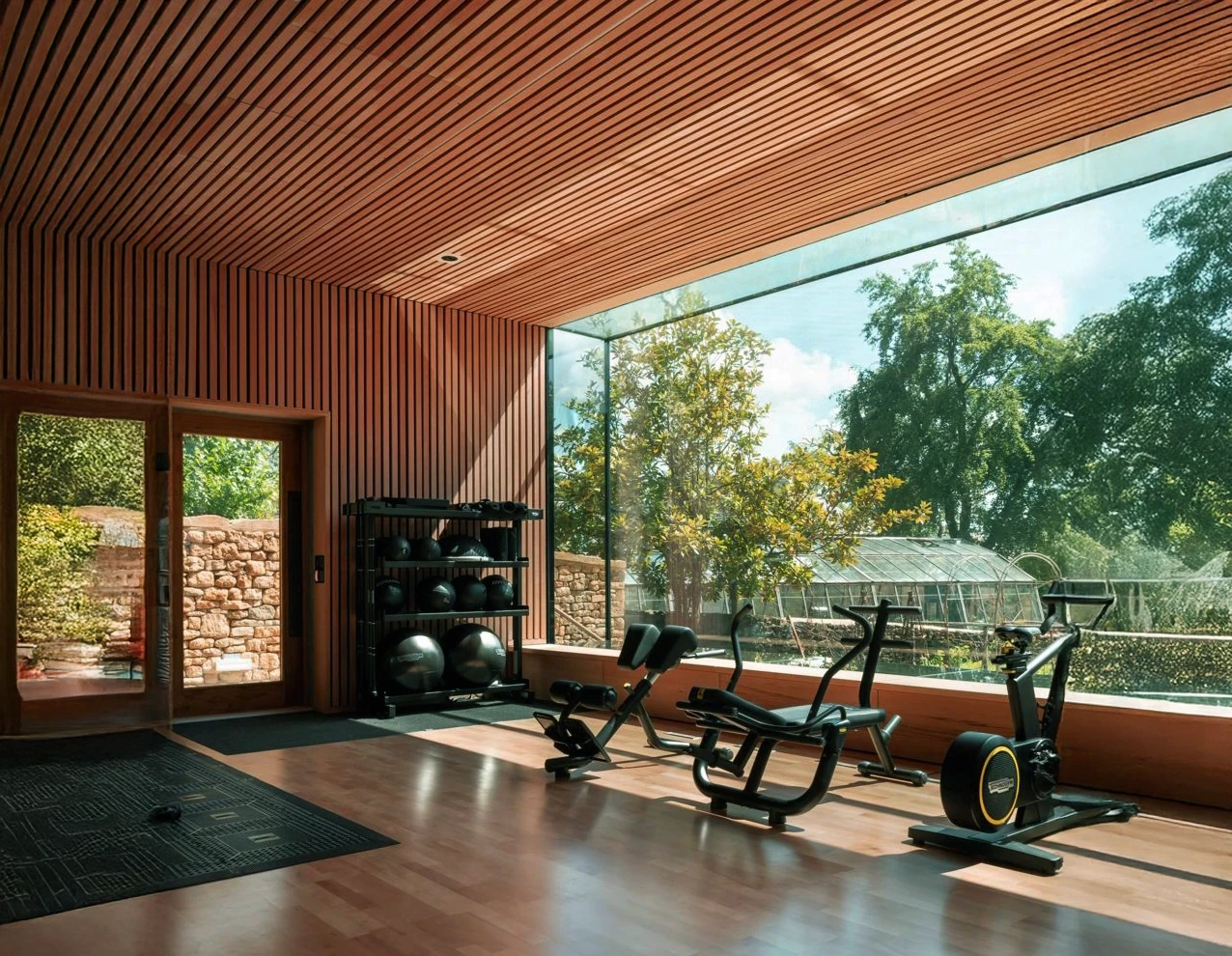Wood-paneled gym with exercise machines and a large window view.