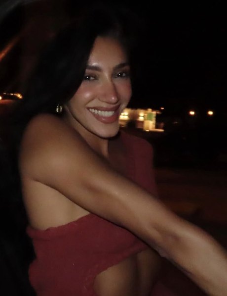 A woman in red smiling on a terrace at night
