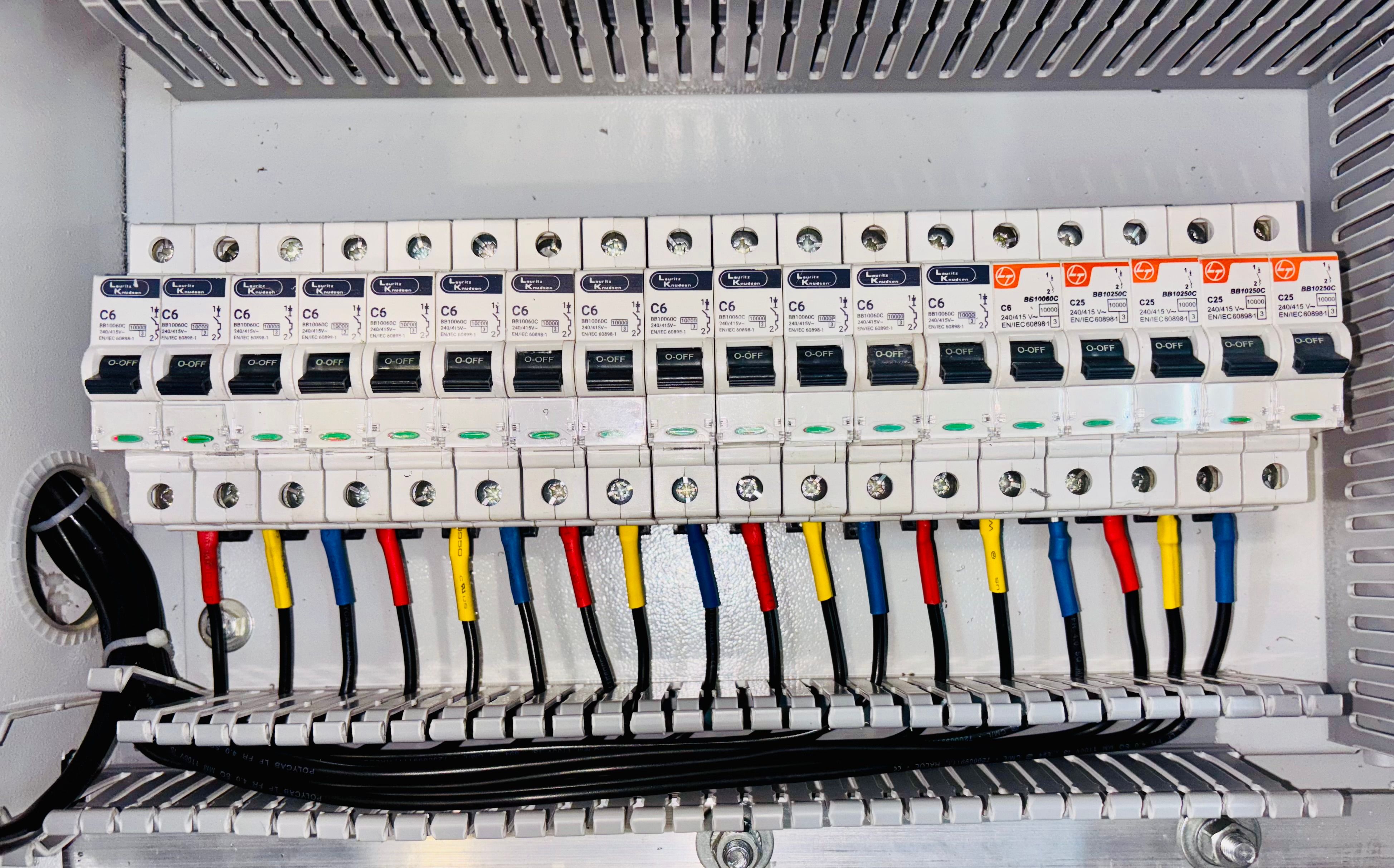 Electrical distribution board with circuit breakers and color-coded wiring.