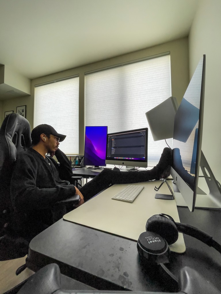 Juan Abad sitting at his desk with multiple computer monitors in front of him