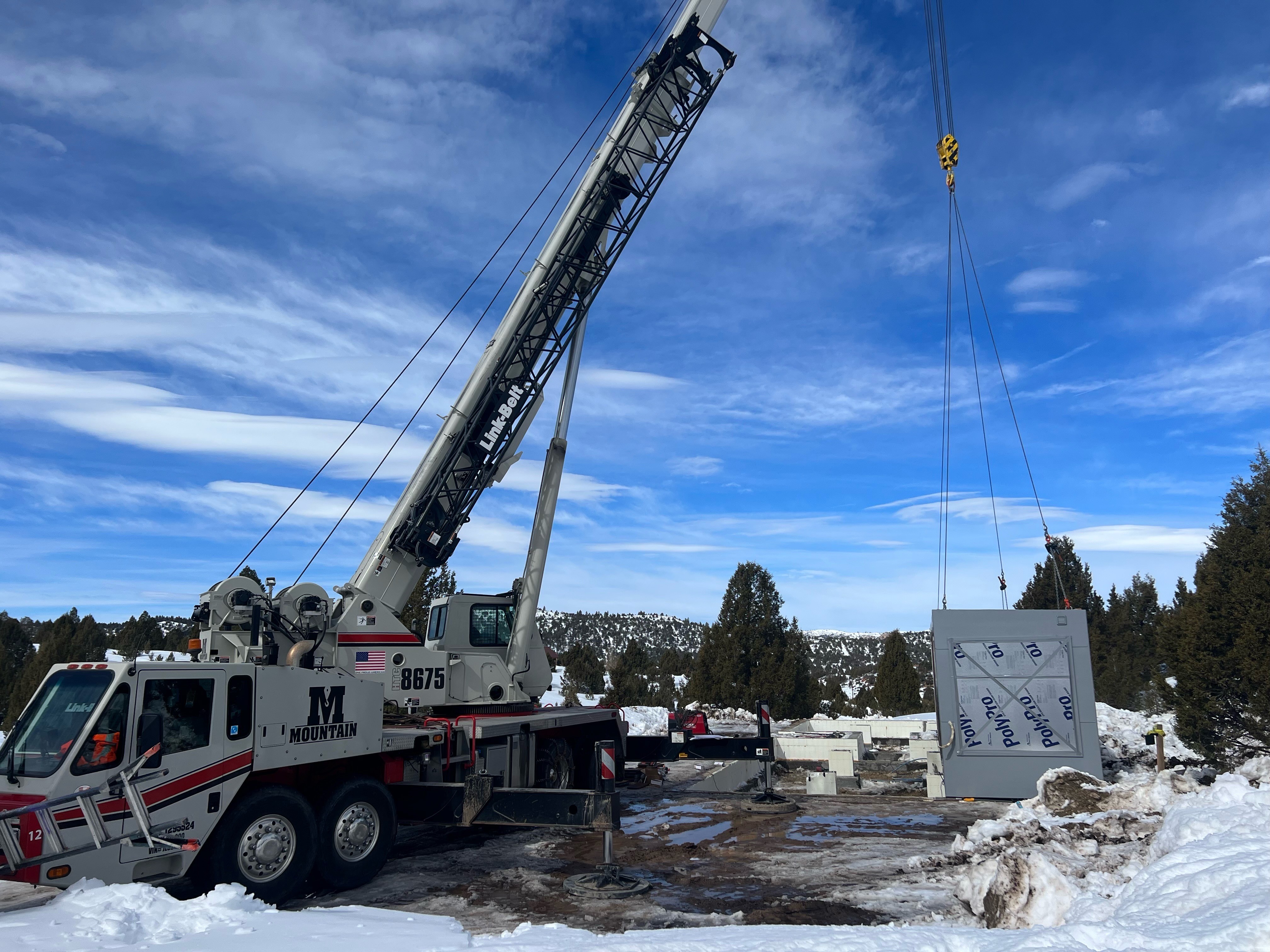 Crane lifting a modular home in the winter.