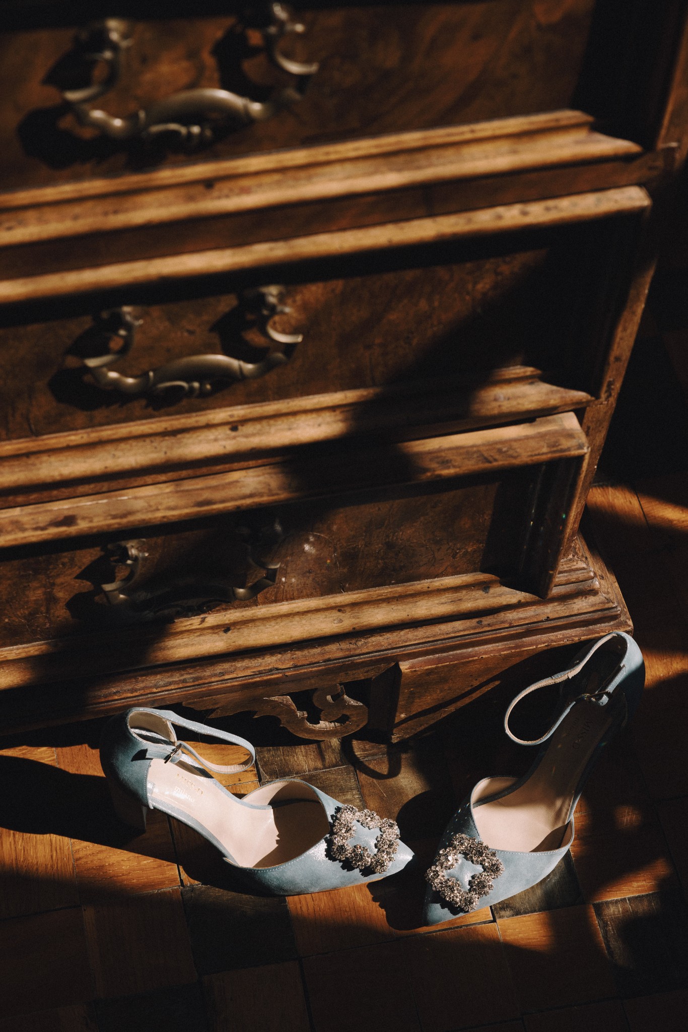 Scarpe da sposa bianche e anelli su gradini in legno antico del Castello di Tabiano, dettaglio di matrimonio
