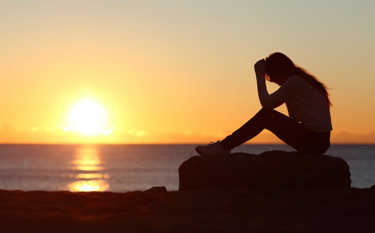 a woman watching a calm sunset representing relief and coping with high-functioning anxiety and stress
