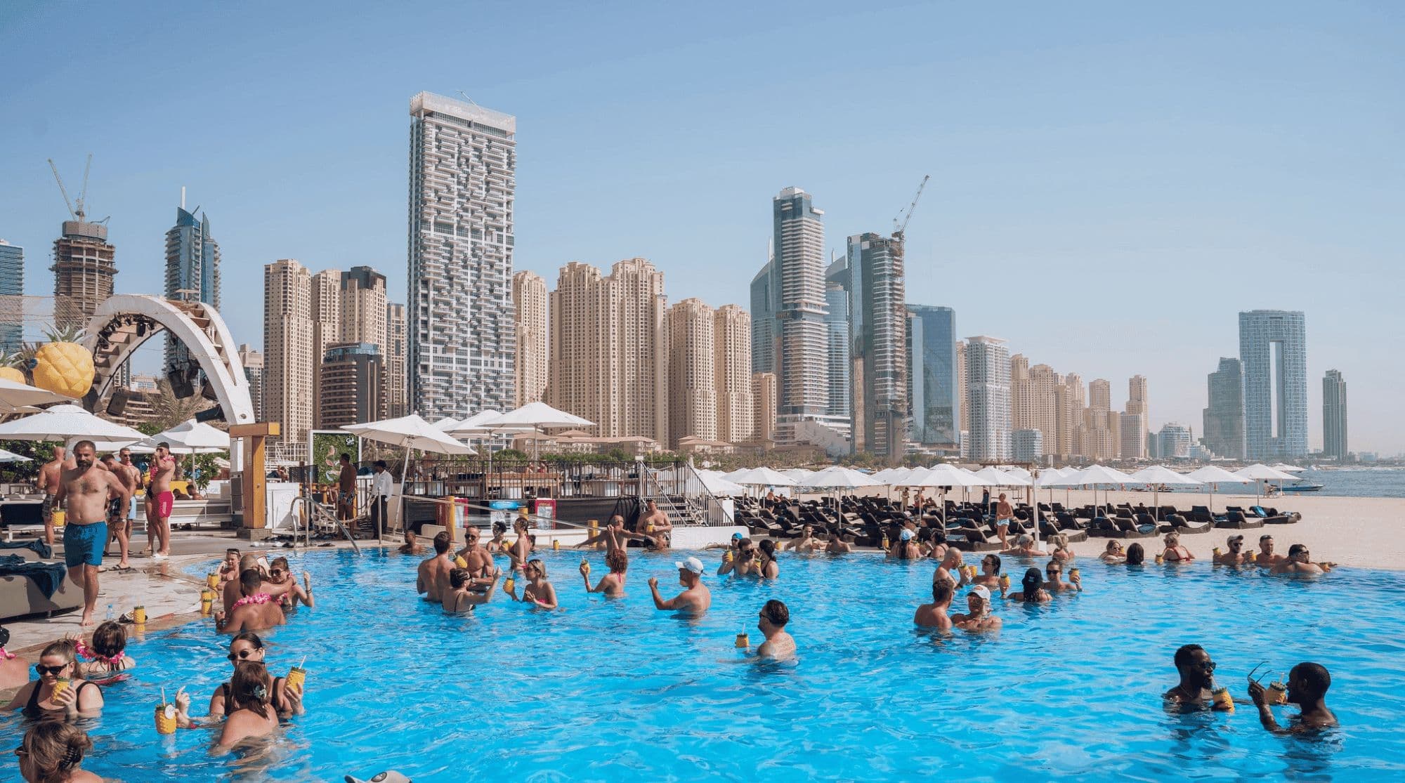 People swimming and hanging out by the pool in Zero Gravity with a view of the city skyline.