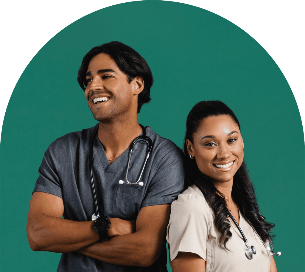 Male and female nurse standing in front of a green background, smiling at the camera.