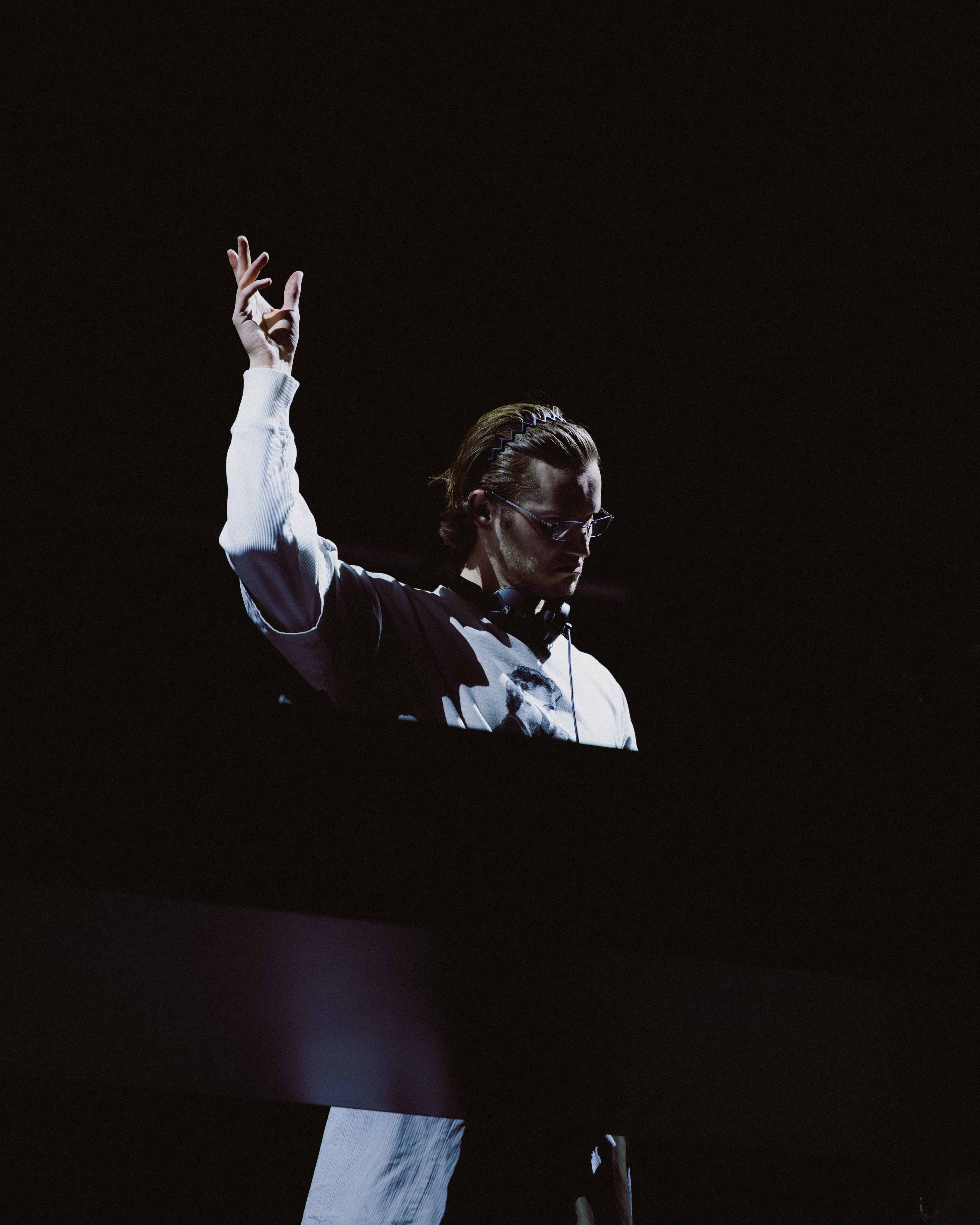 MAU P performing live at Coachella 2025 with hand raised behind the decks under dramatic spotlight, captured by A World Away creative director Brandon Densley