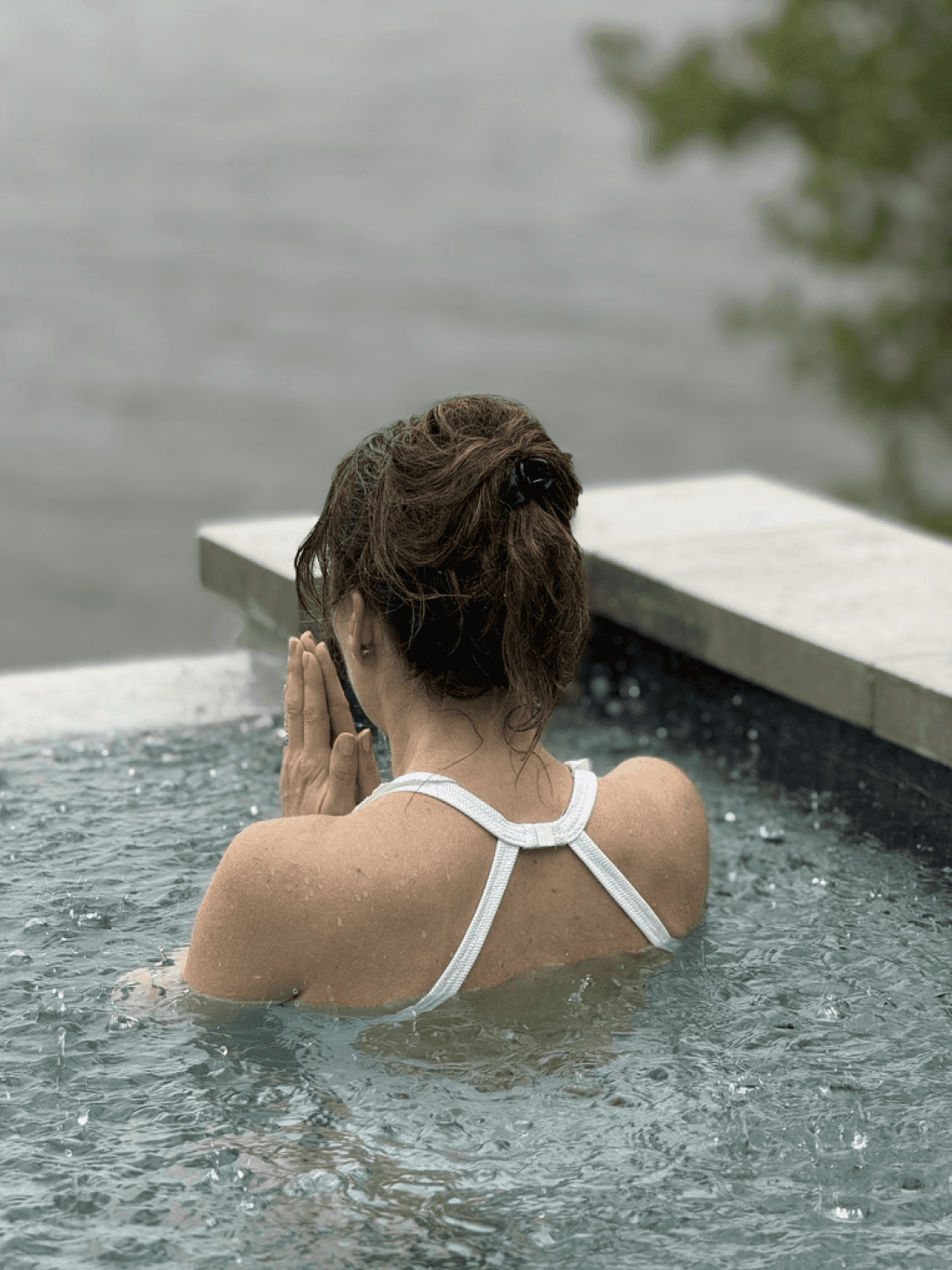A modern, serene spa features a tranquil indoor pool with geometric stepping stones, surrounded by soft lighting and minimalist decor, while two individuals in swimwear relax by the water.