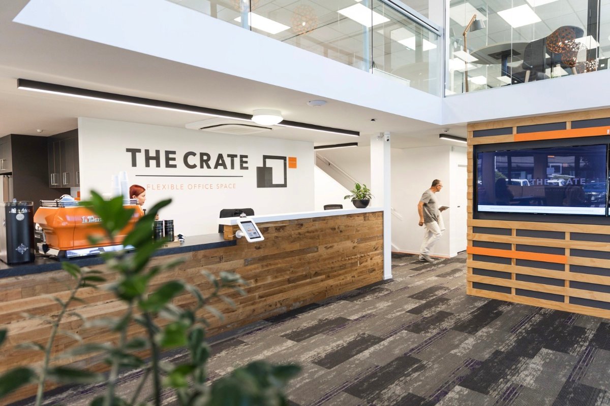 Wide shot of the reception desk at The Crate Albany-Rosedale, with the receptionist behind the desk and a community member in the background.