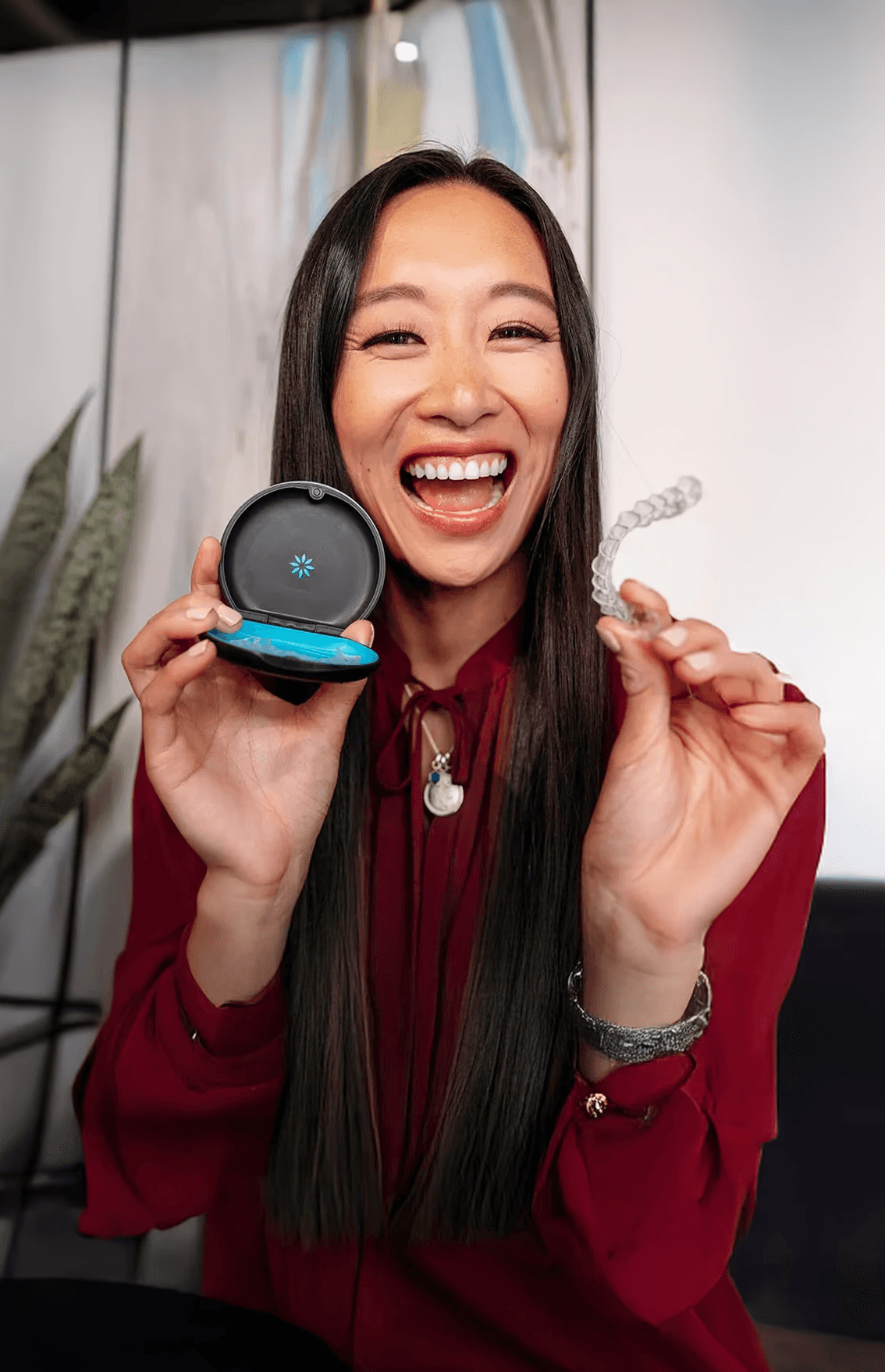 Invisalign in Dubai with a woman smiling confidently, holding her clear aligners, highlighting discreet and effective treatment.