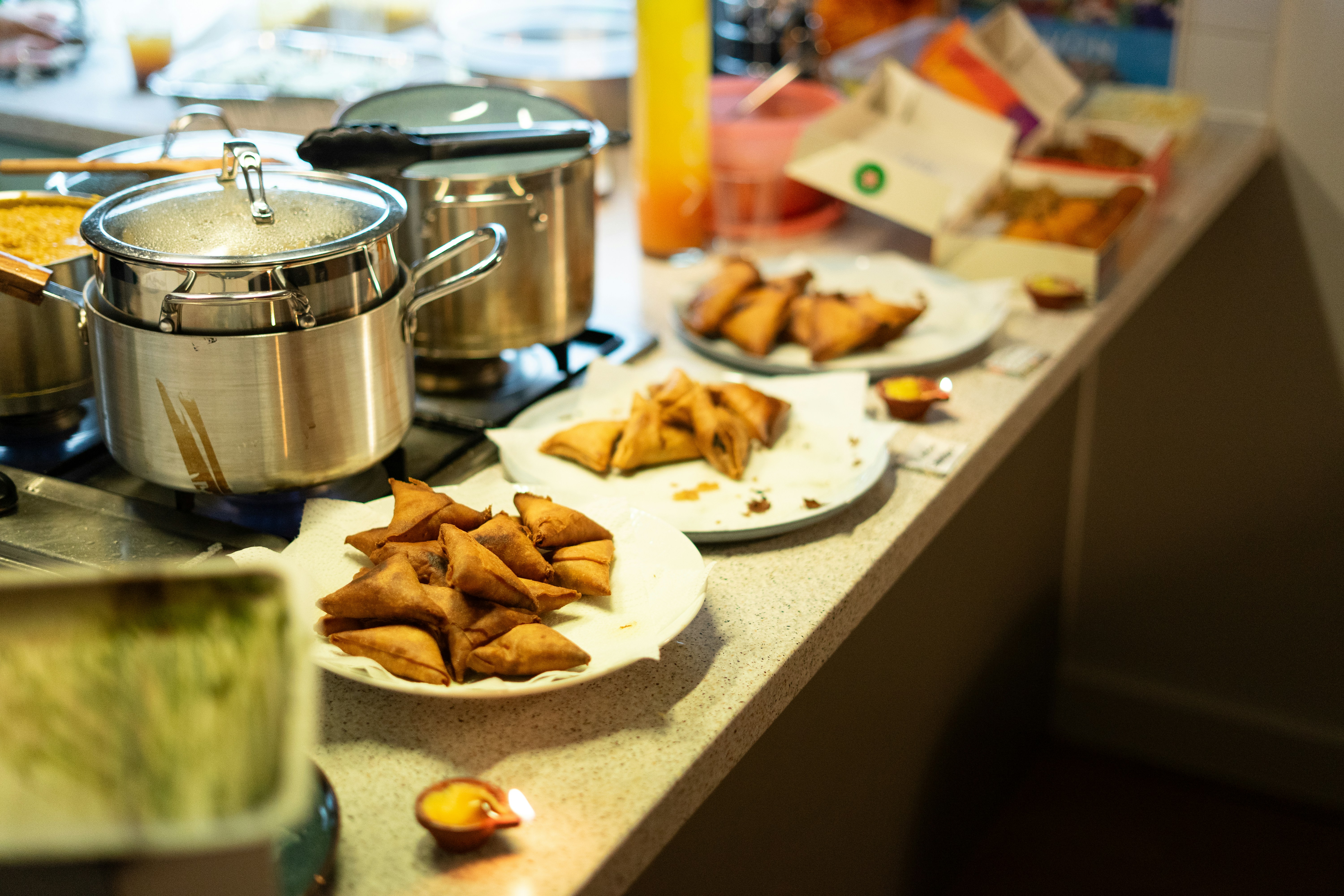 Samosas and food served on plates on a counter.
