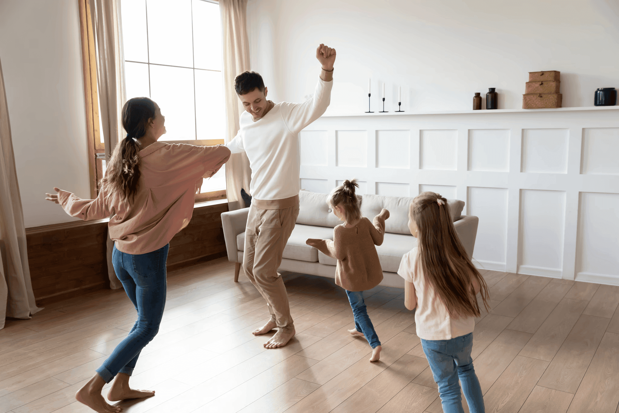 A happy family dances barefoot together on LUXO’s hybrid flooring, showcasing its warm, comfortable feel and durable surface. The smooth wood finish enhances the cosy living room atmosphere, reflecting LUXO’s promise of safe, long-lasting, and family-friendly flooring made for real everyday moments.