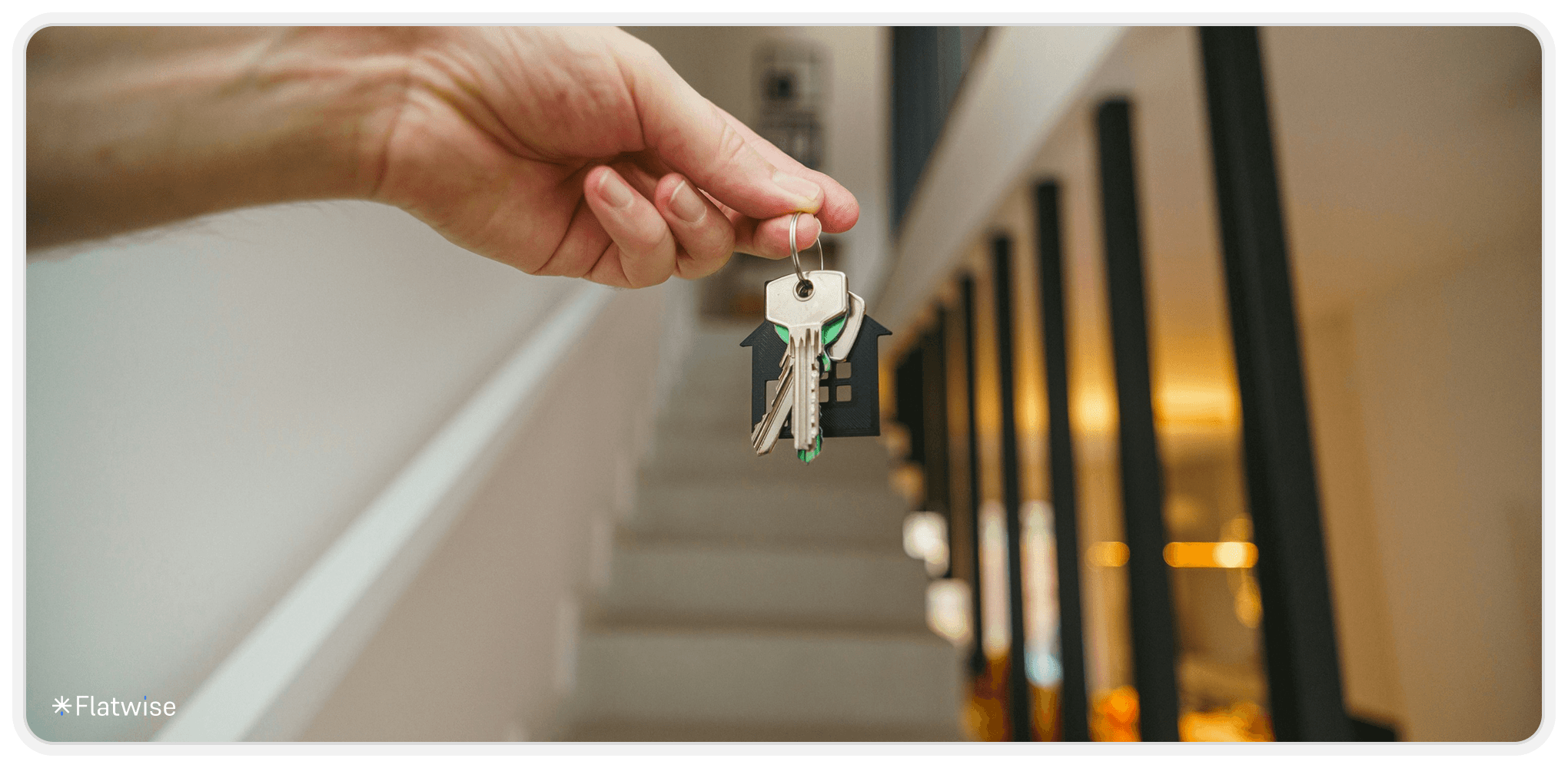 Eine Hand mit einem Schlüssel vor einem Stiegenaufgang