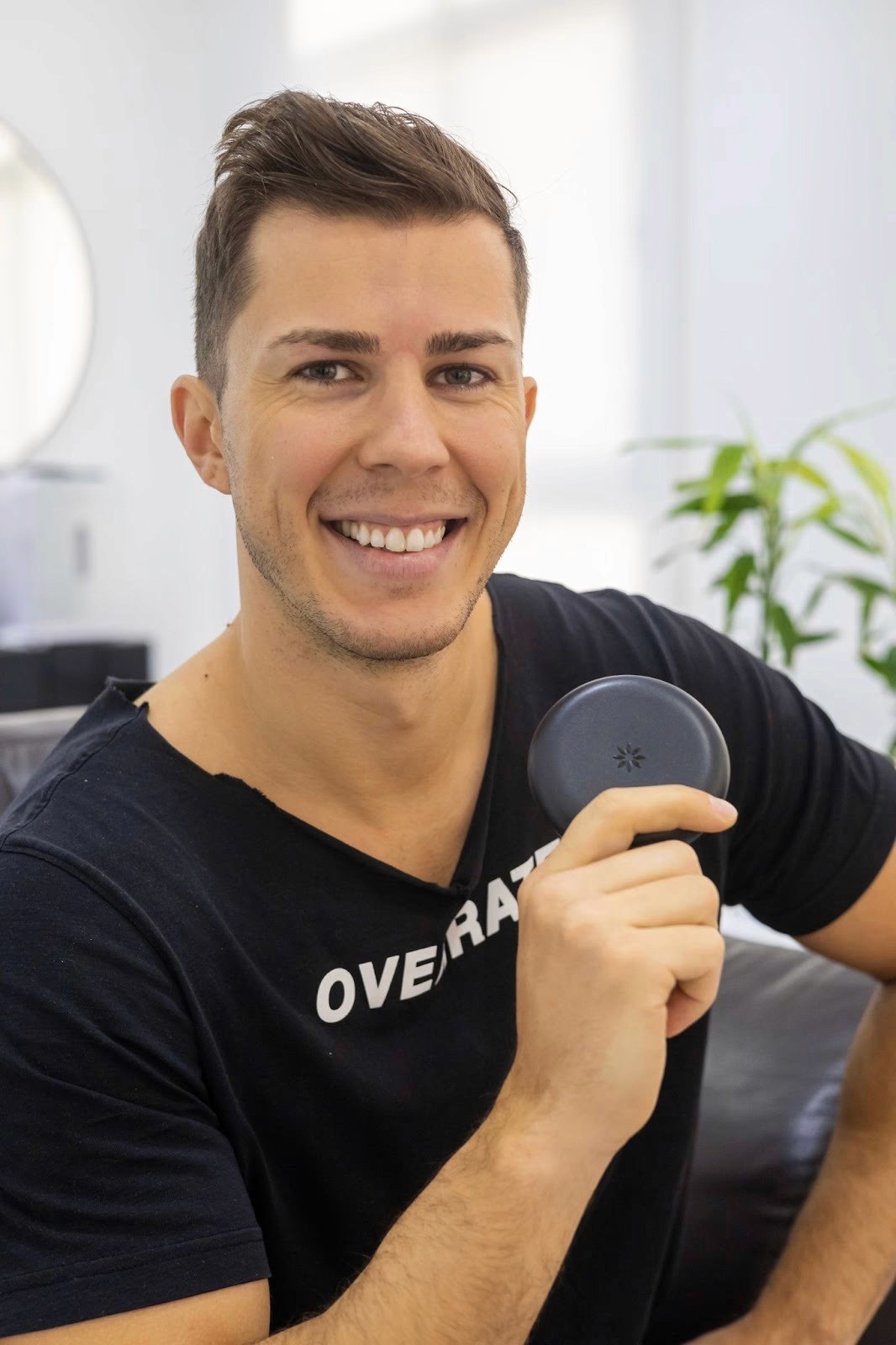 طبيب يبتسم مبتعدًا وهو يمسك ريتينر الأسنان باللون الأسود