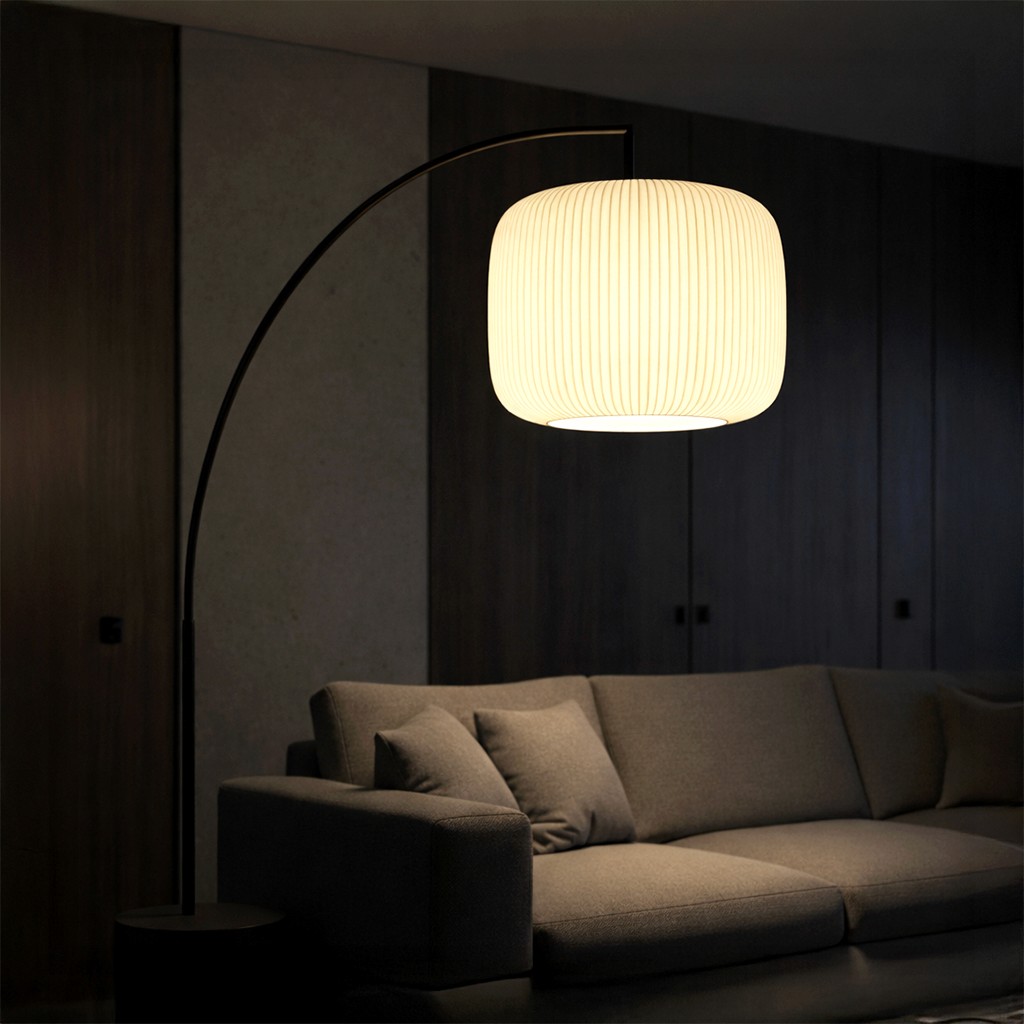 Glowing arched floor lamp hanging over a sofa in a dark room.