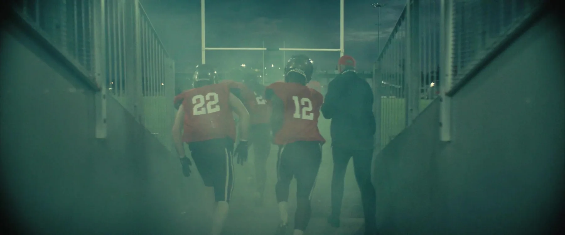 Back of a football player's helmet facing a fog-filled stadium at night