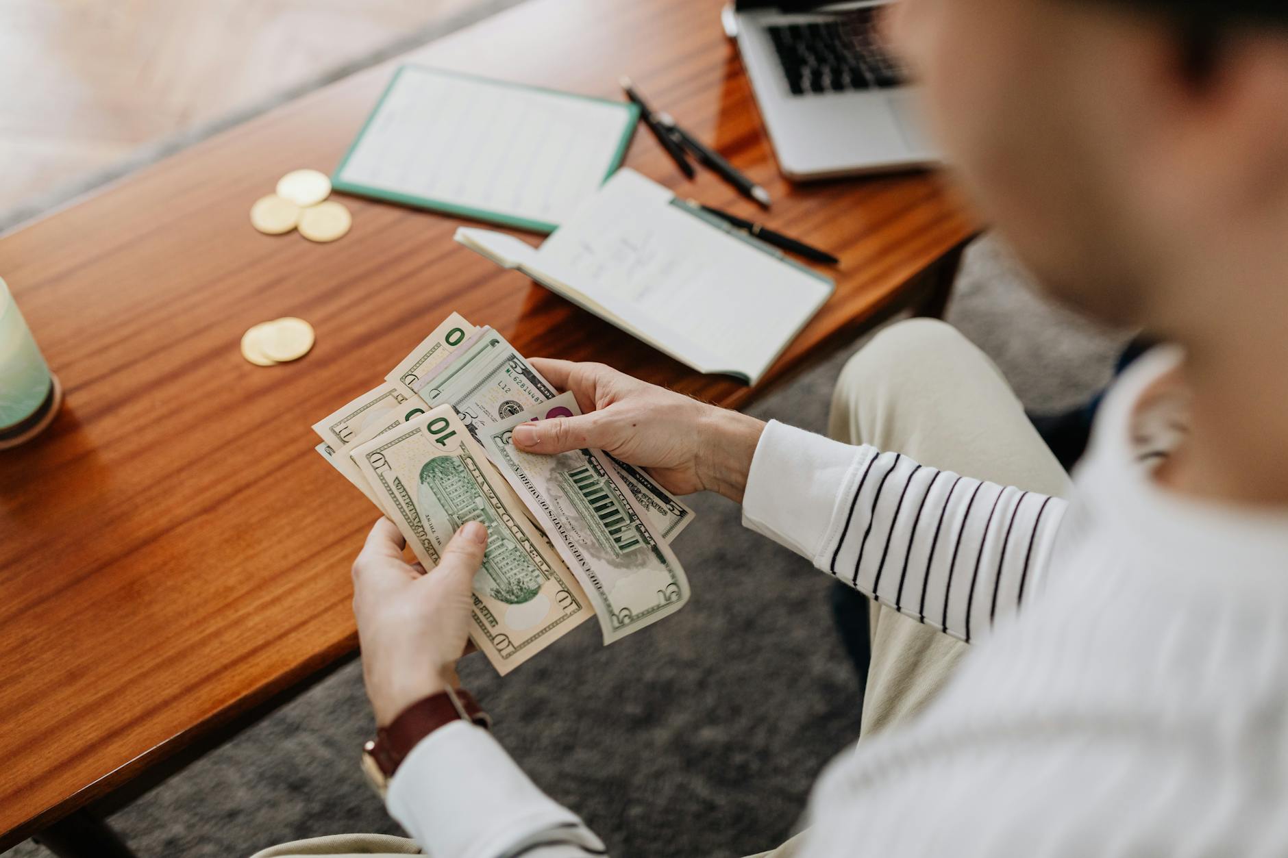 A teenager practices life skills by counting paper money and coins on a kitchen table during a math lesson.