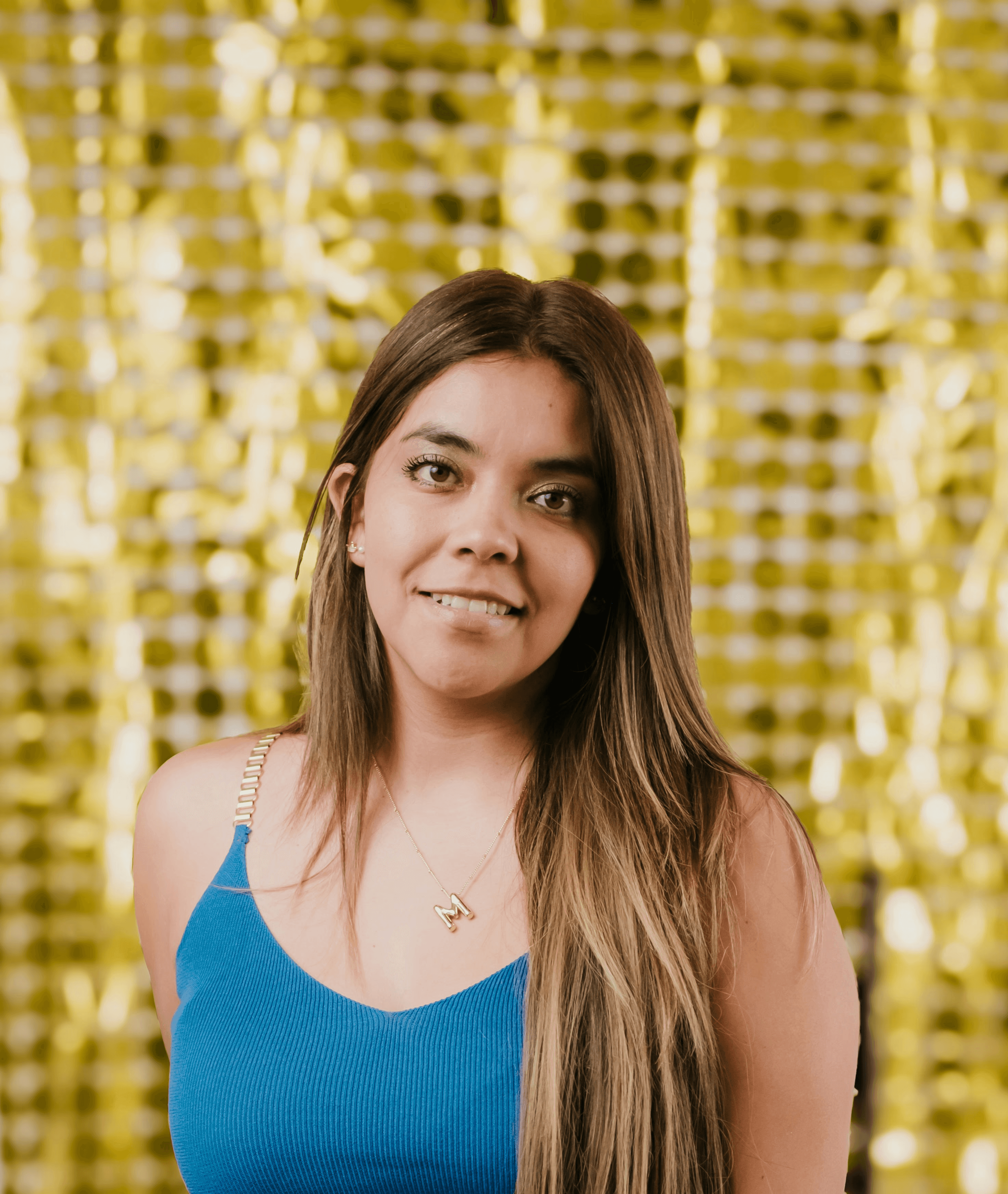 A woman sitting on a chair in front of a gold curtain