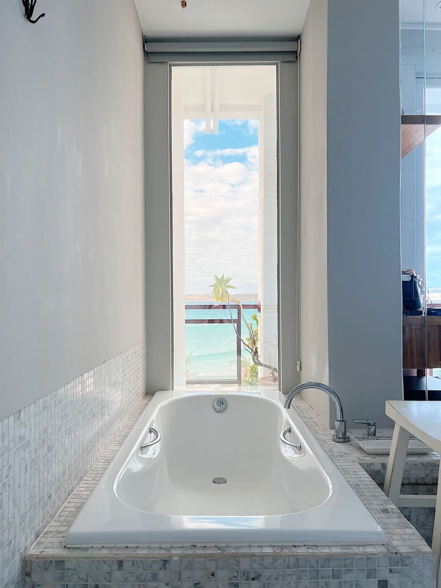 Bright bathroom in the deluxe sea view room with a bathtub and ocean view through the window.