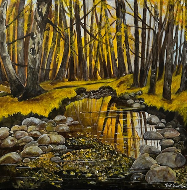 A tranquil scene of a pond, nearly completely still save for the slight ripples of wind, reflects the golden forest surrounding it.