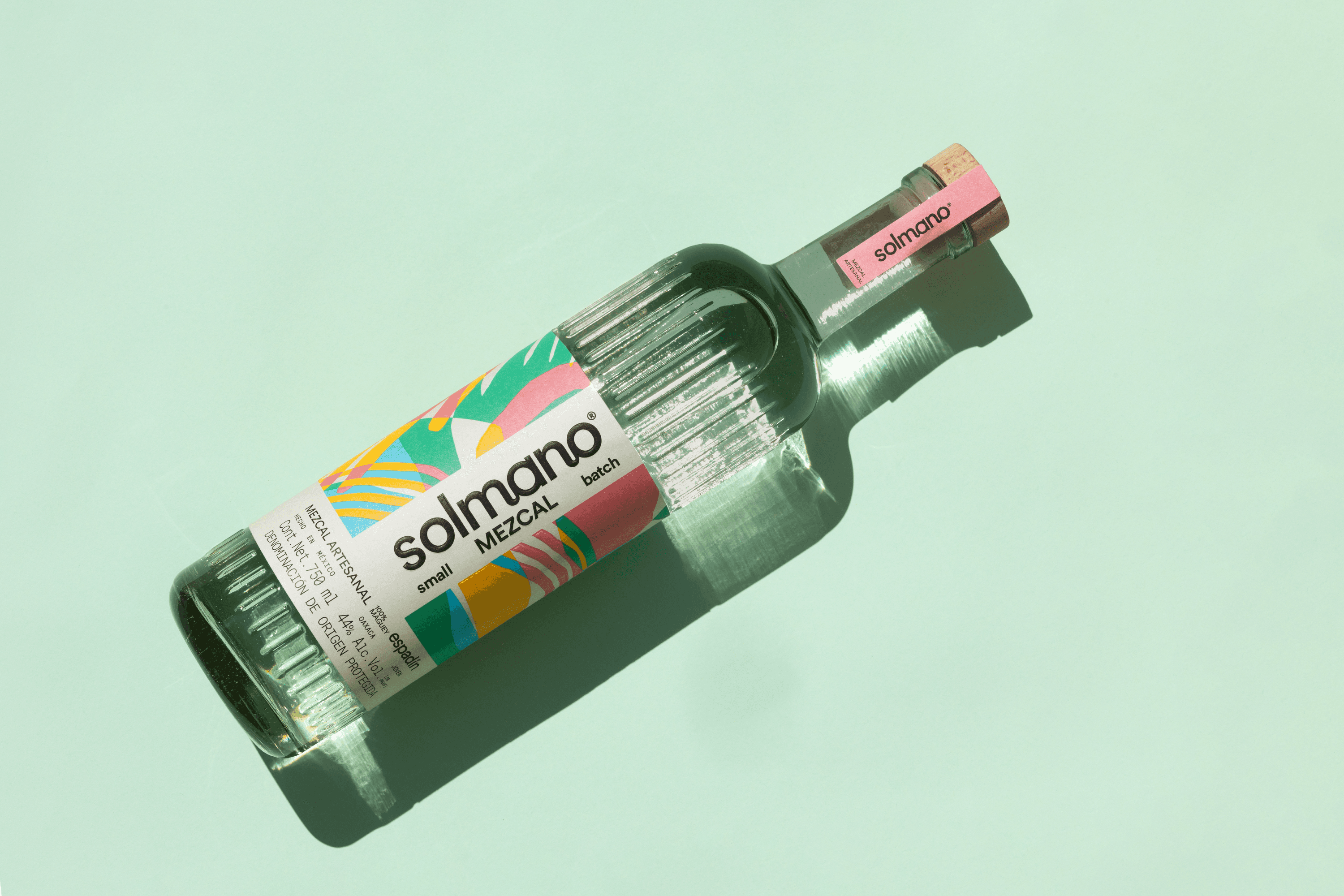 Solmano Espadin mezcal bottle lying on a mint green background