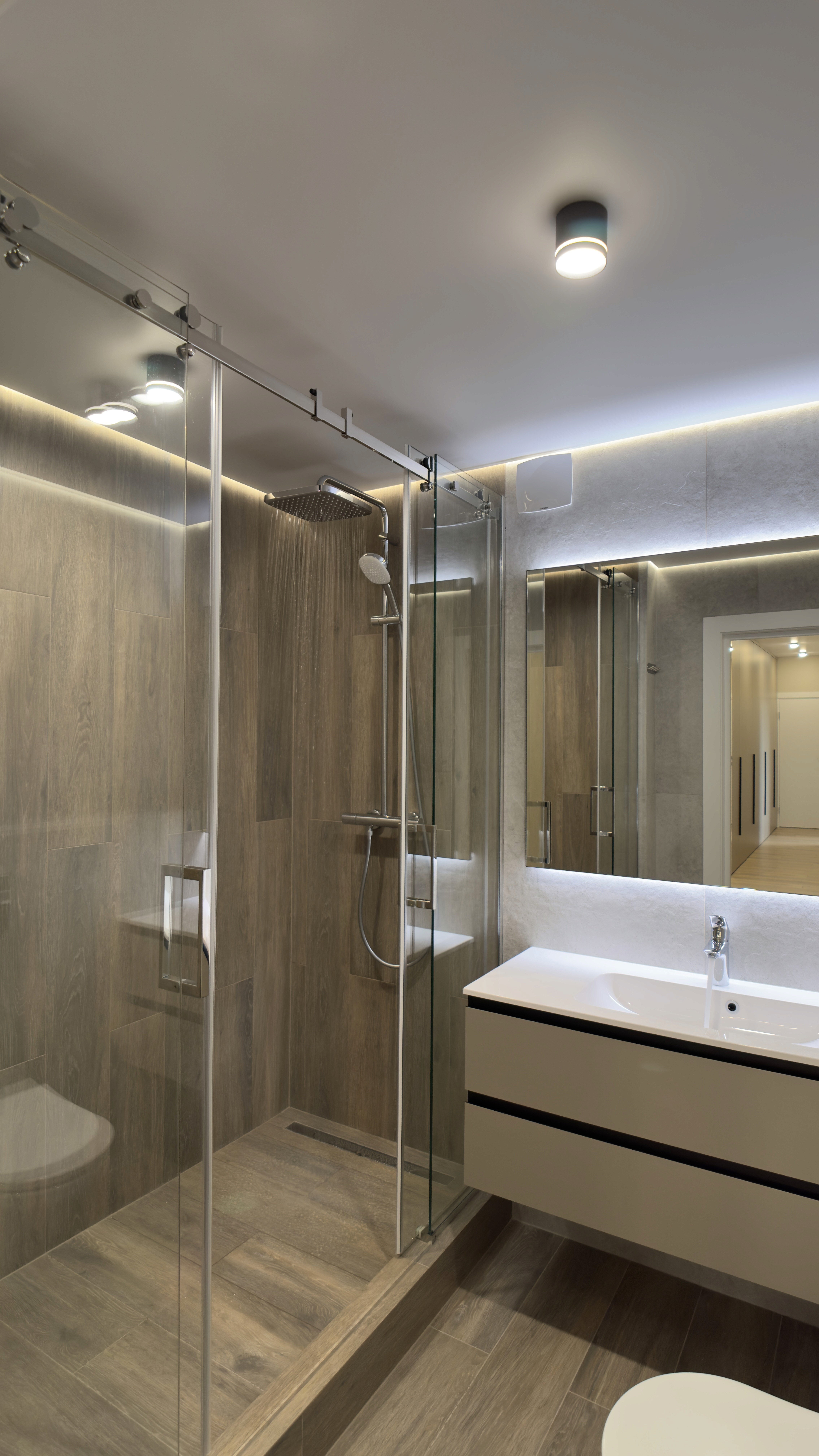 Сучасна ванна кімната з душовою кабіною, великим дзеркалом і меблями у світлих тонах