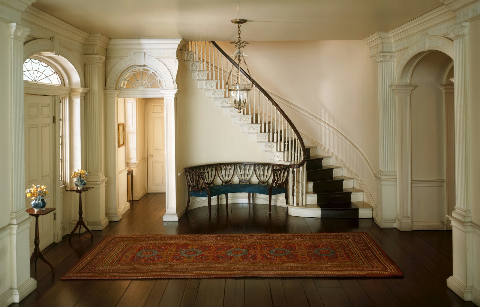 An entrance hall with a sweeping staircase and a patterned rug