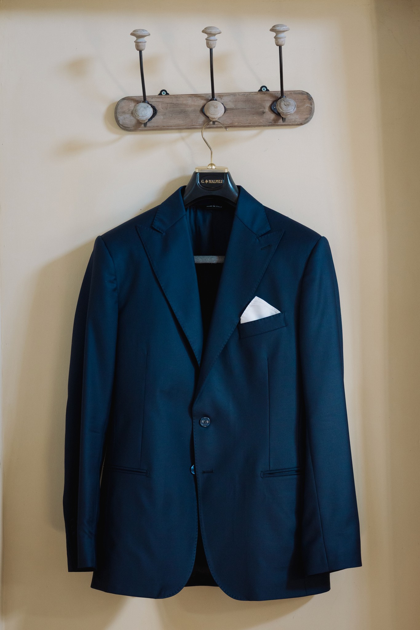 Giacca blu dello sposo appesa al gancio in legno, preparativi matrimonio al Castello di Scipione