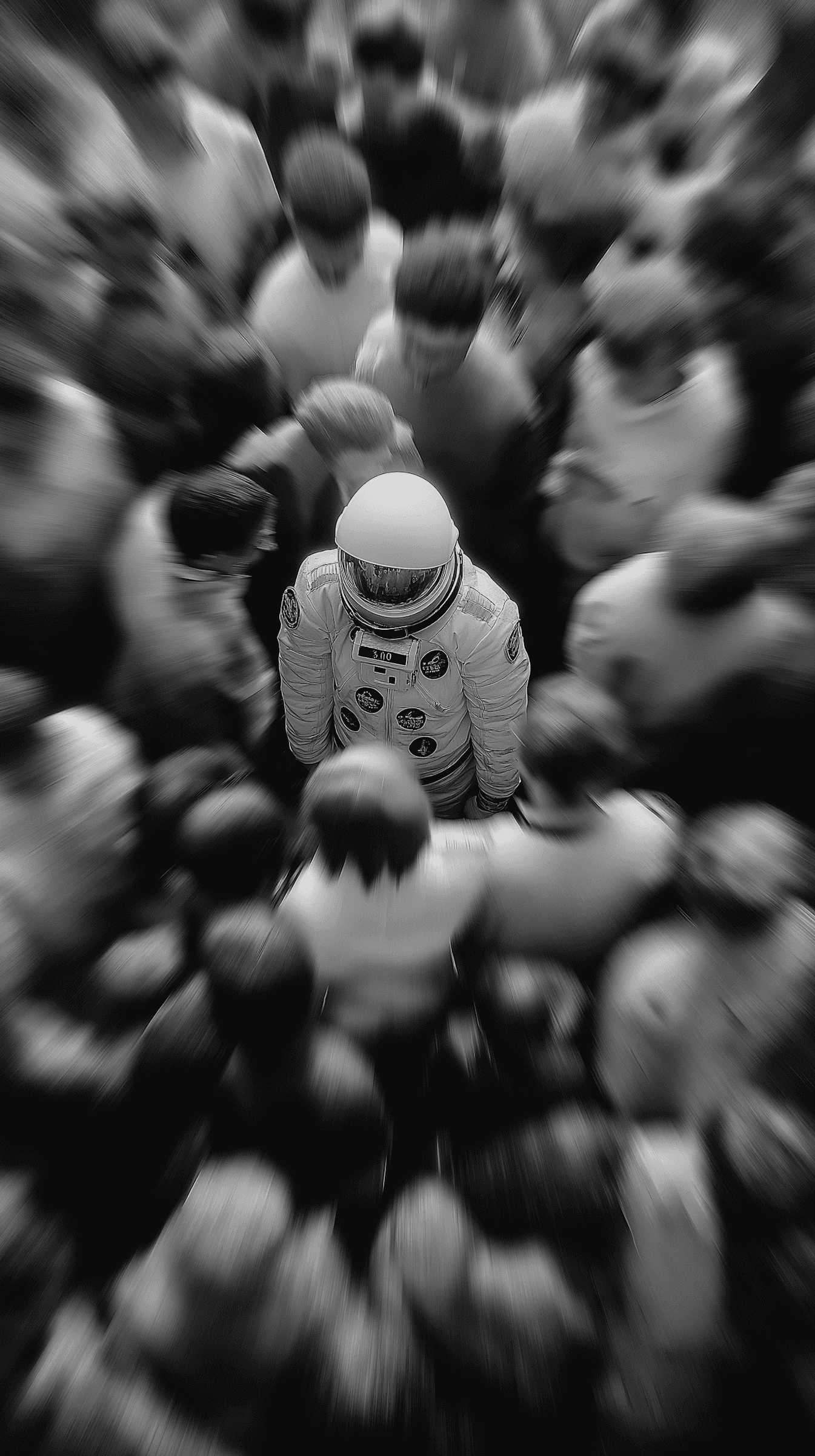 Astronaut surrounded by blurred crowd in black and white