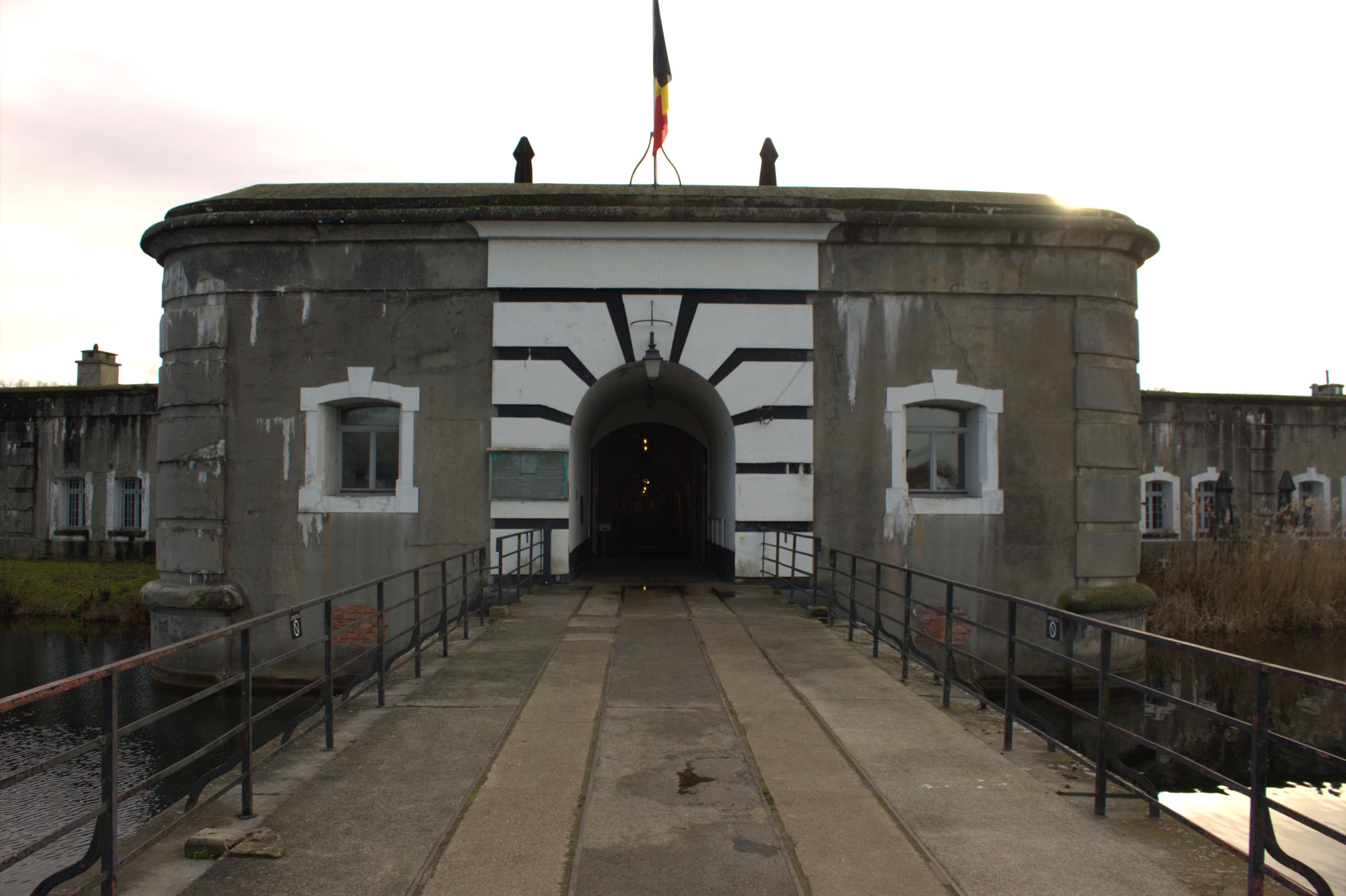 Escape Fort Liezele: voorkant historisch fort met vlag bovenop en entreepoort – unieke escape room locatie in Puurs Antwerpen regio