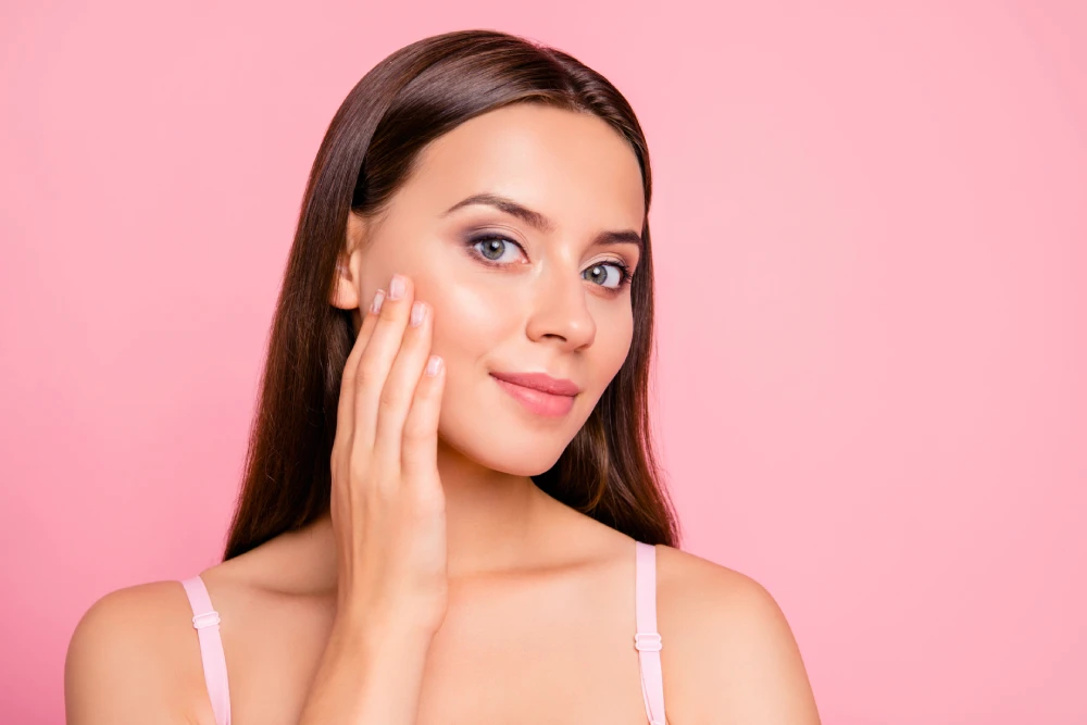 Woman with glowing skin touching her cheek after a PRP vampire facial.